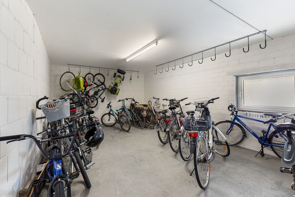 Fahrradraum mit vielen geparkten und an der Wand hängenden Fahrrädern.