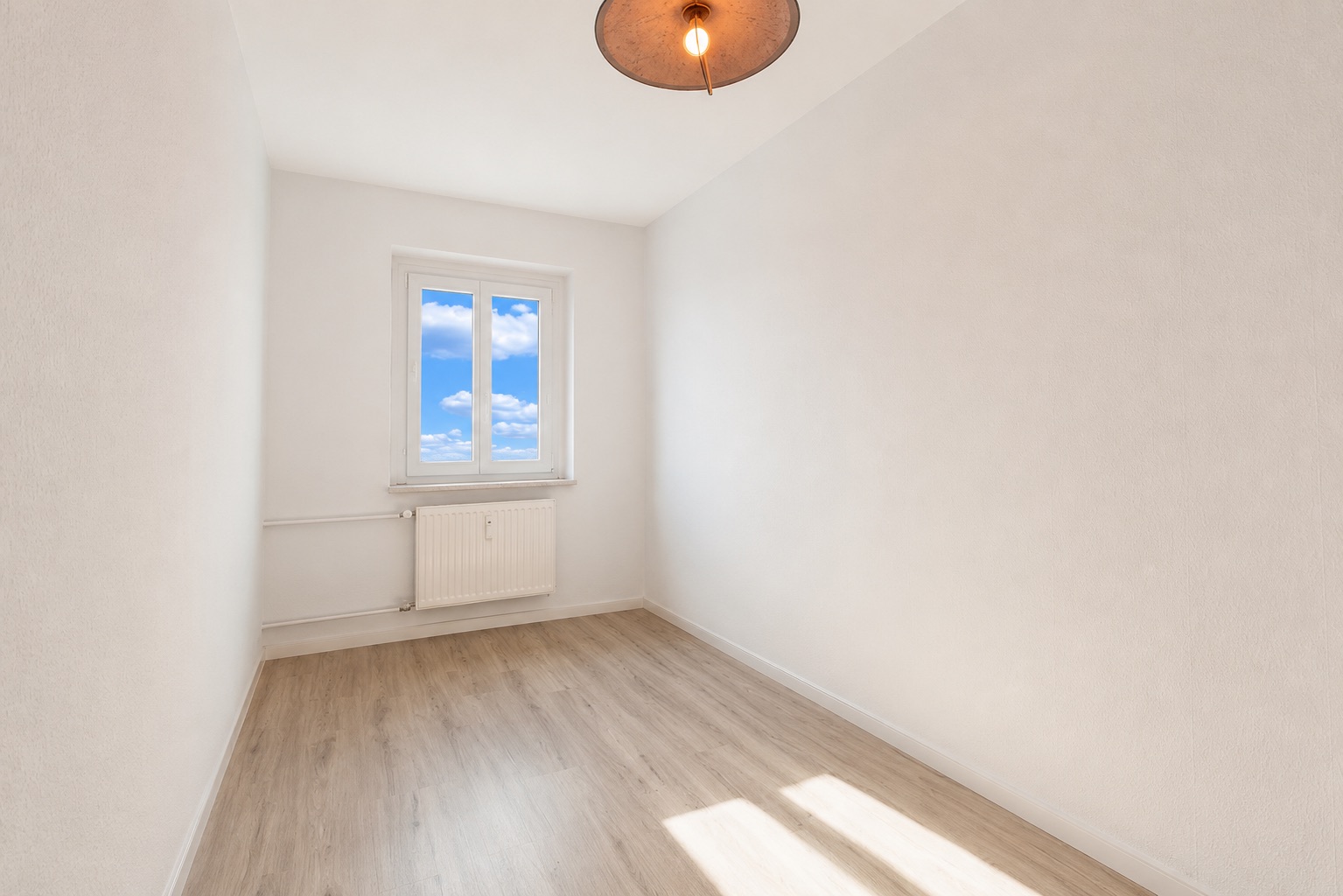 Heller, leerer Raum mit Holzfußboden, weißem Fenster und Deckenlampe.