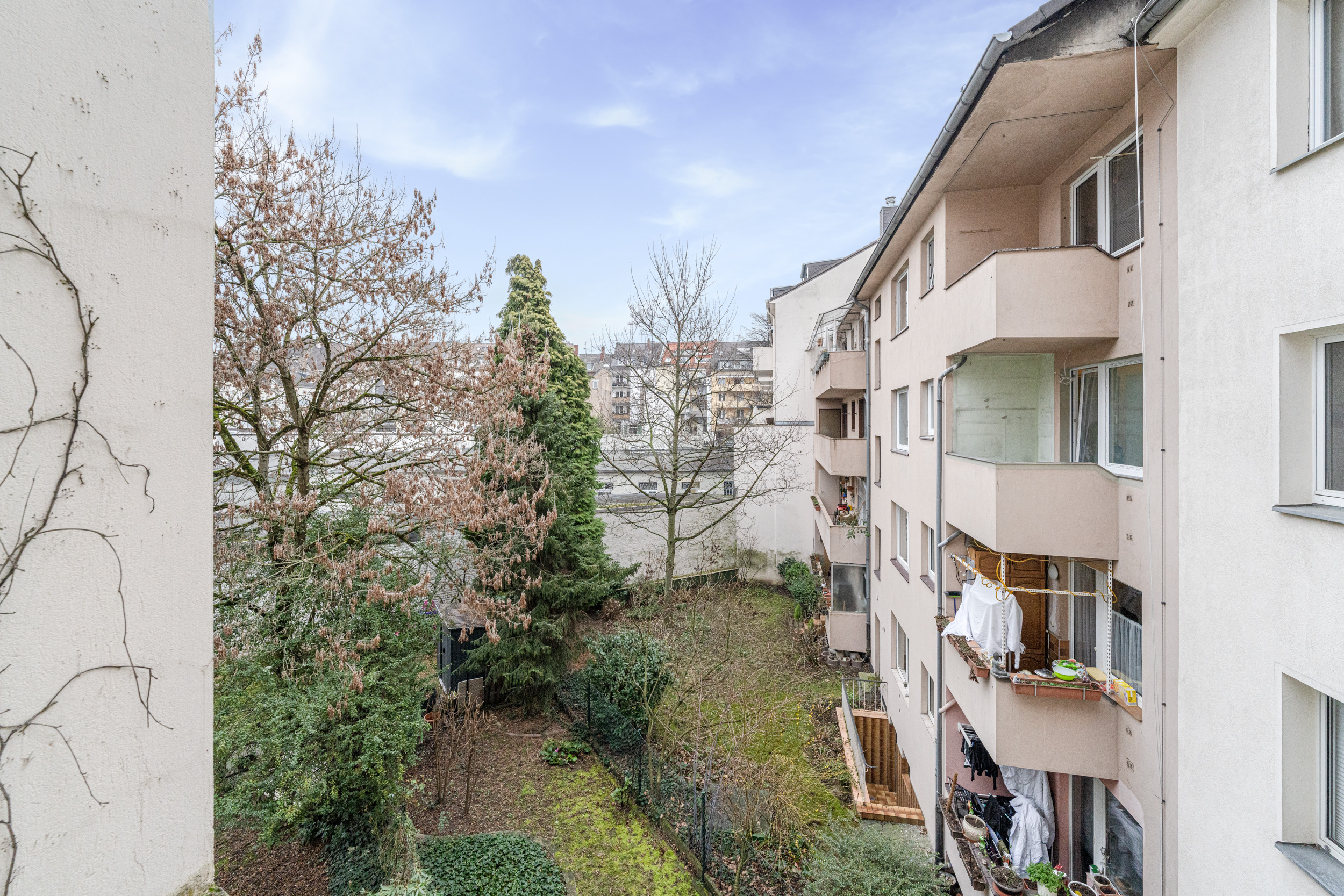 Blick auf einen Innenhof mit Bäumen und Balkonen eines Wohnhauses.