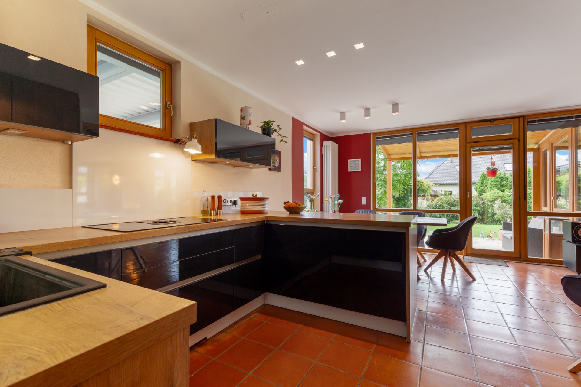 Moderne Küche mit Holzmöbeln und großem Fenster, Essbereich und Blick auf den Garten.
