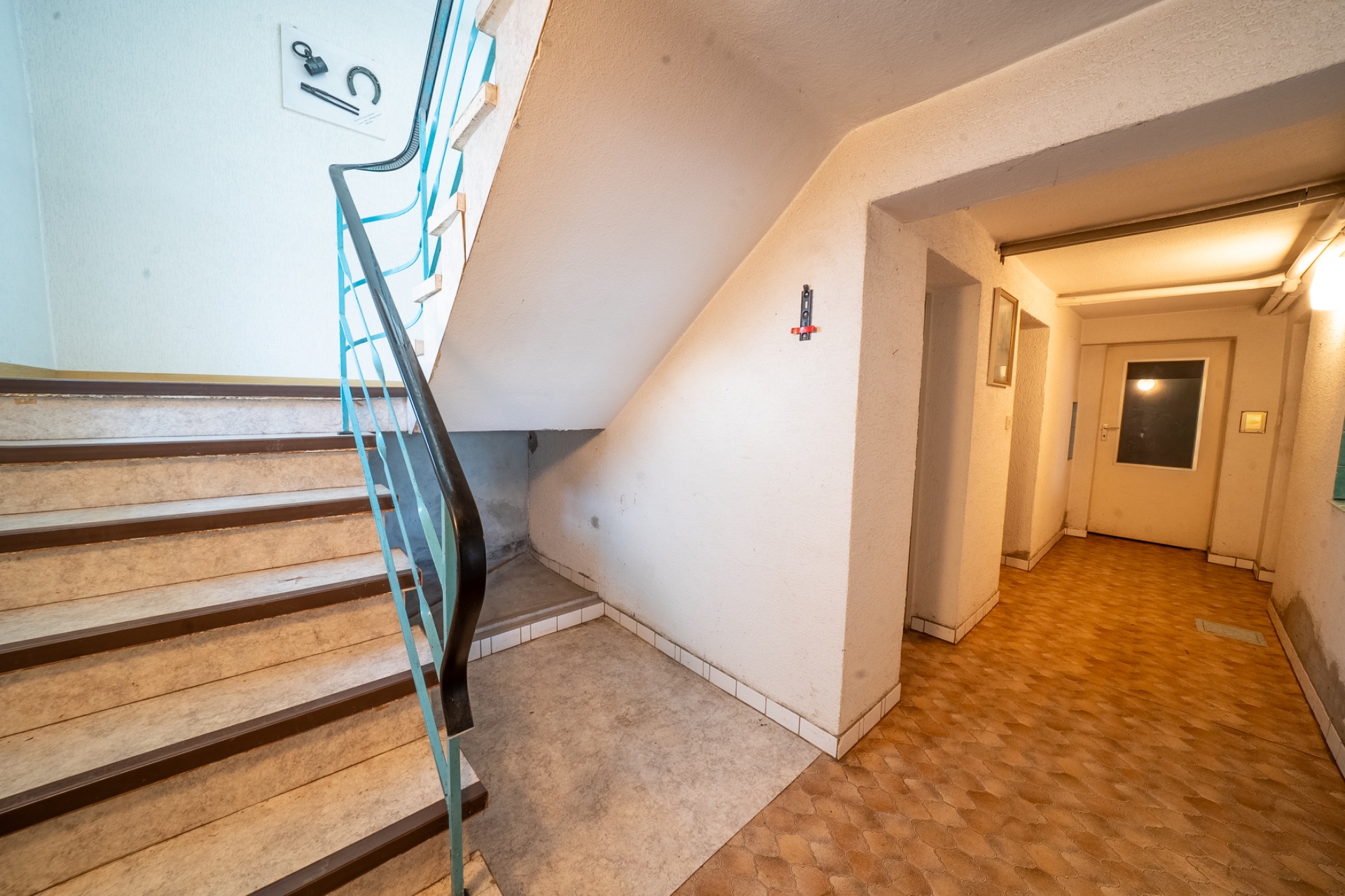Treppenhaus mit Stufen, Geländer und Flur in einem Wohngebäude.
