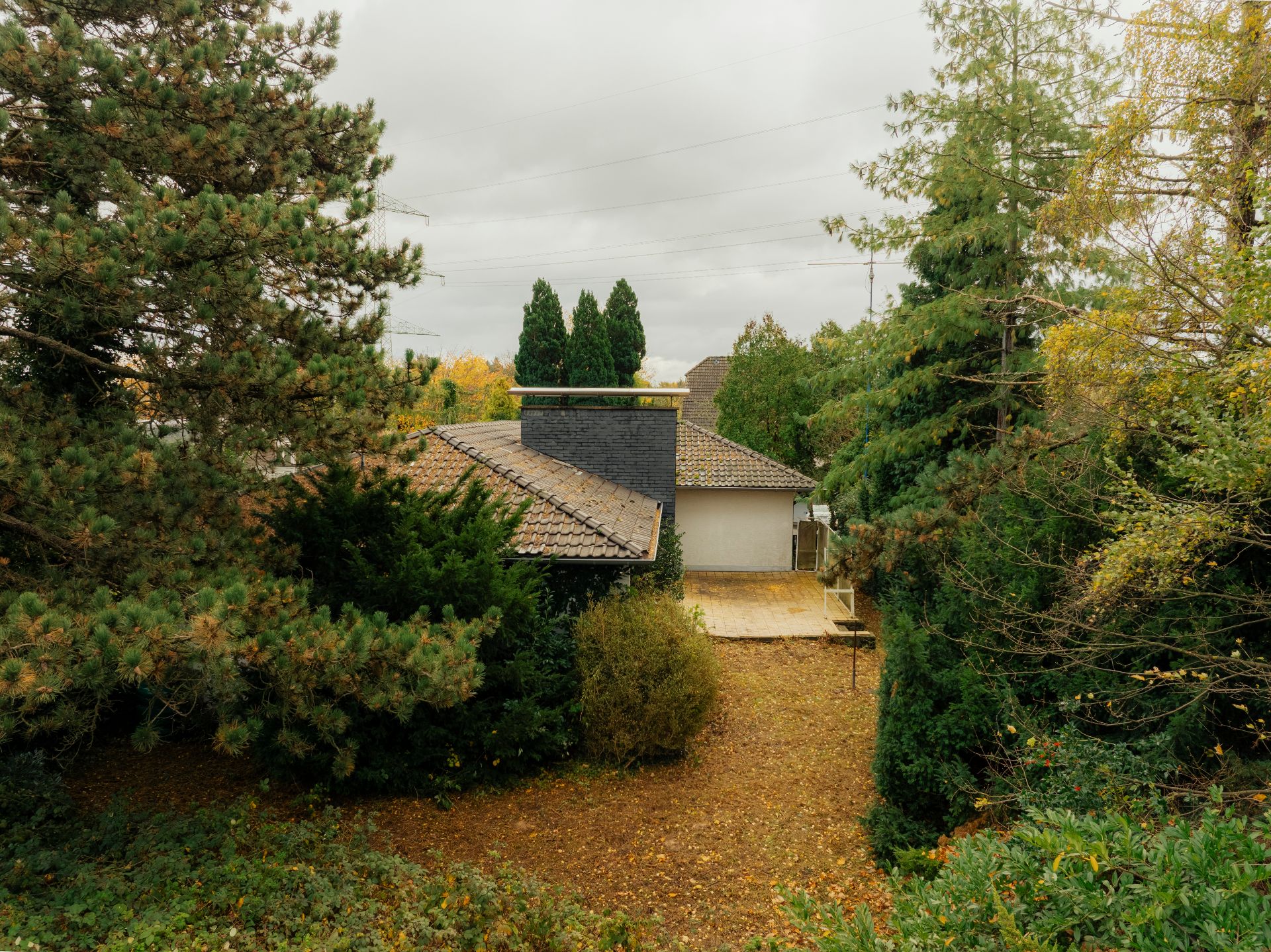 Haus mit grauem Dach, umgeben von Bäumen und herbstlichem Garten.