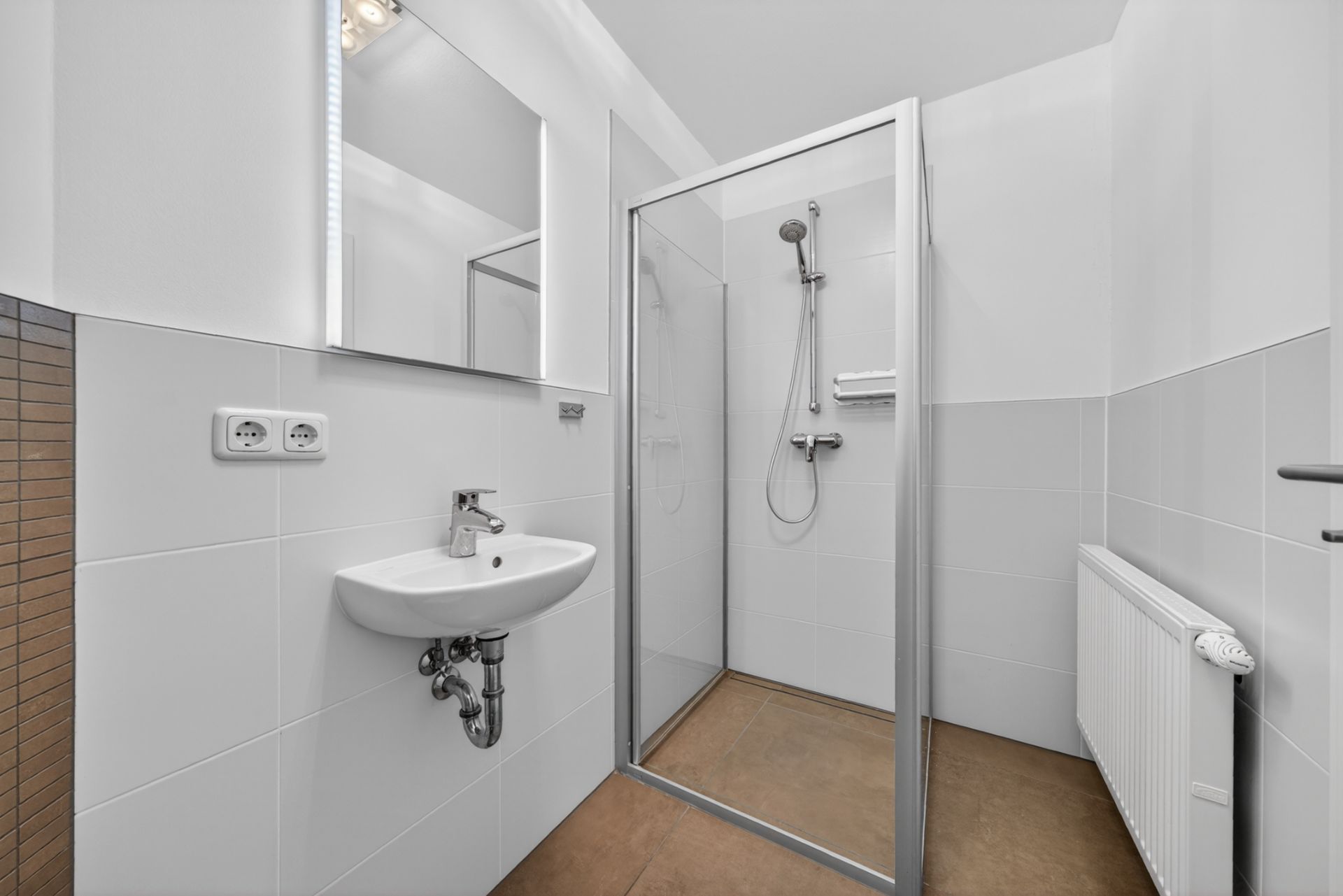 Modernes Badezimmer mit Dusche, Waschbecken, Spiegel und Heizung.