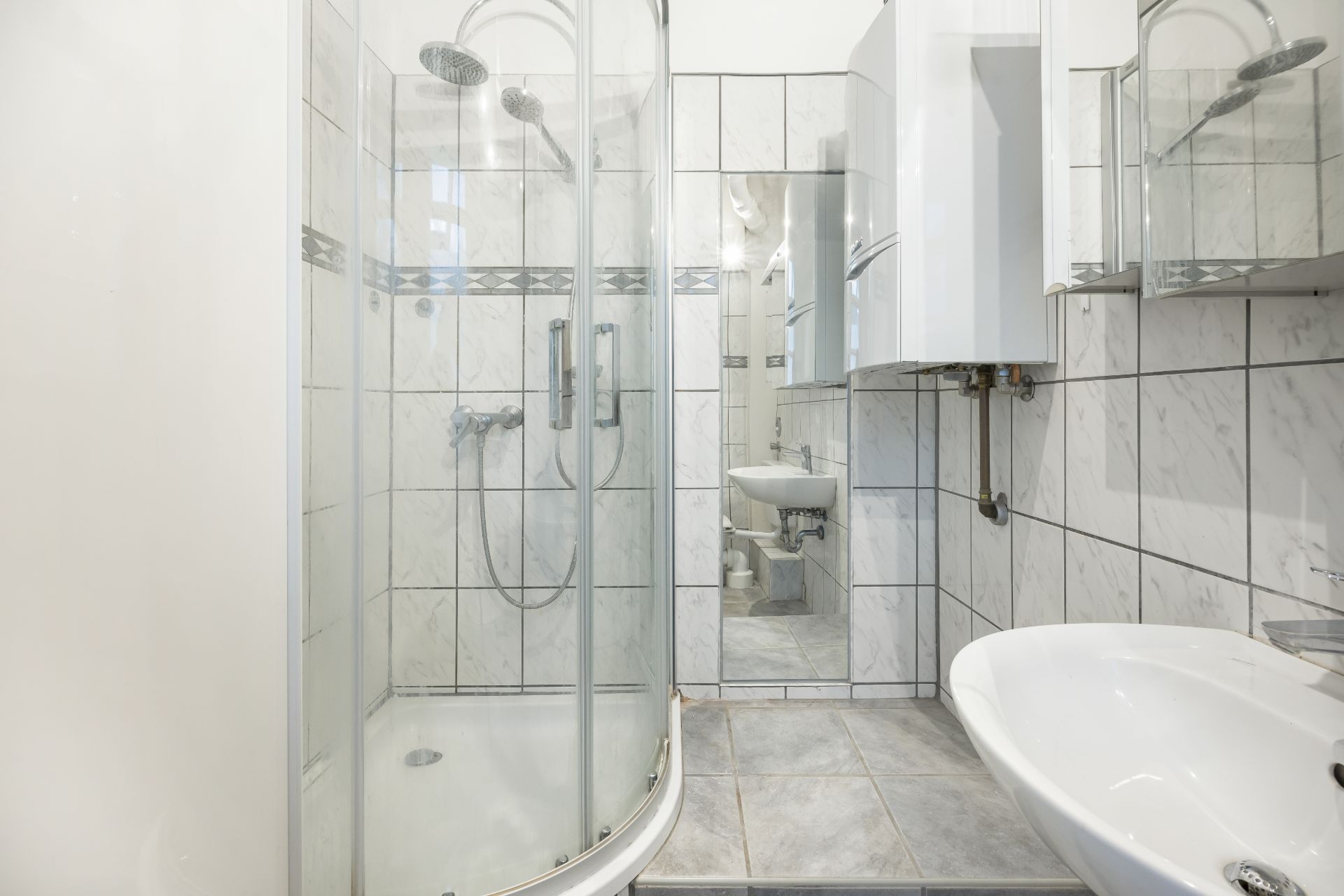Modernes Badezimmer mit Duschkabine, Waschbecken und weißen Fliesen.