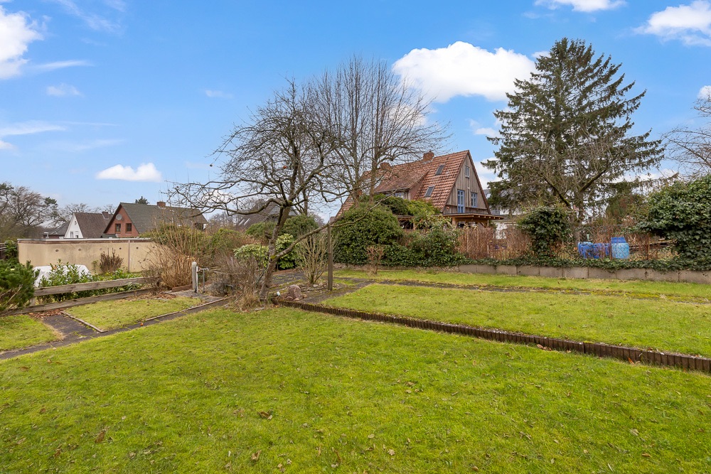 Garten mit Rasenfläche, Gehweg und Bäumen, Einfamilienhaus im Hintergrund.