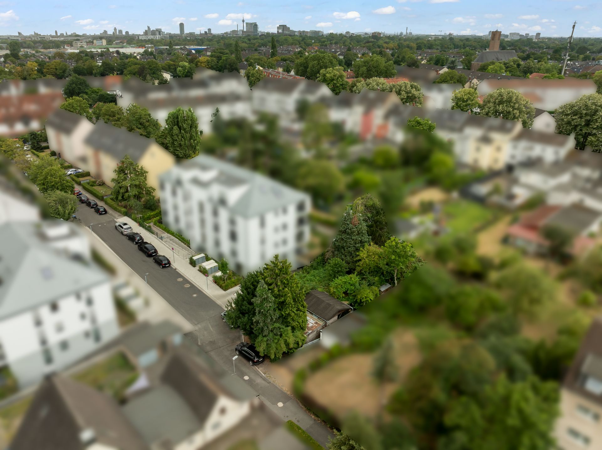 Blick aus der Vogelperspektive auf ein Wohngebiet mit Häusern, Bäumen und einer Straße.