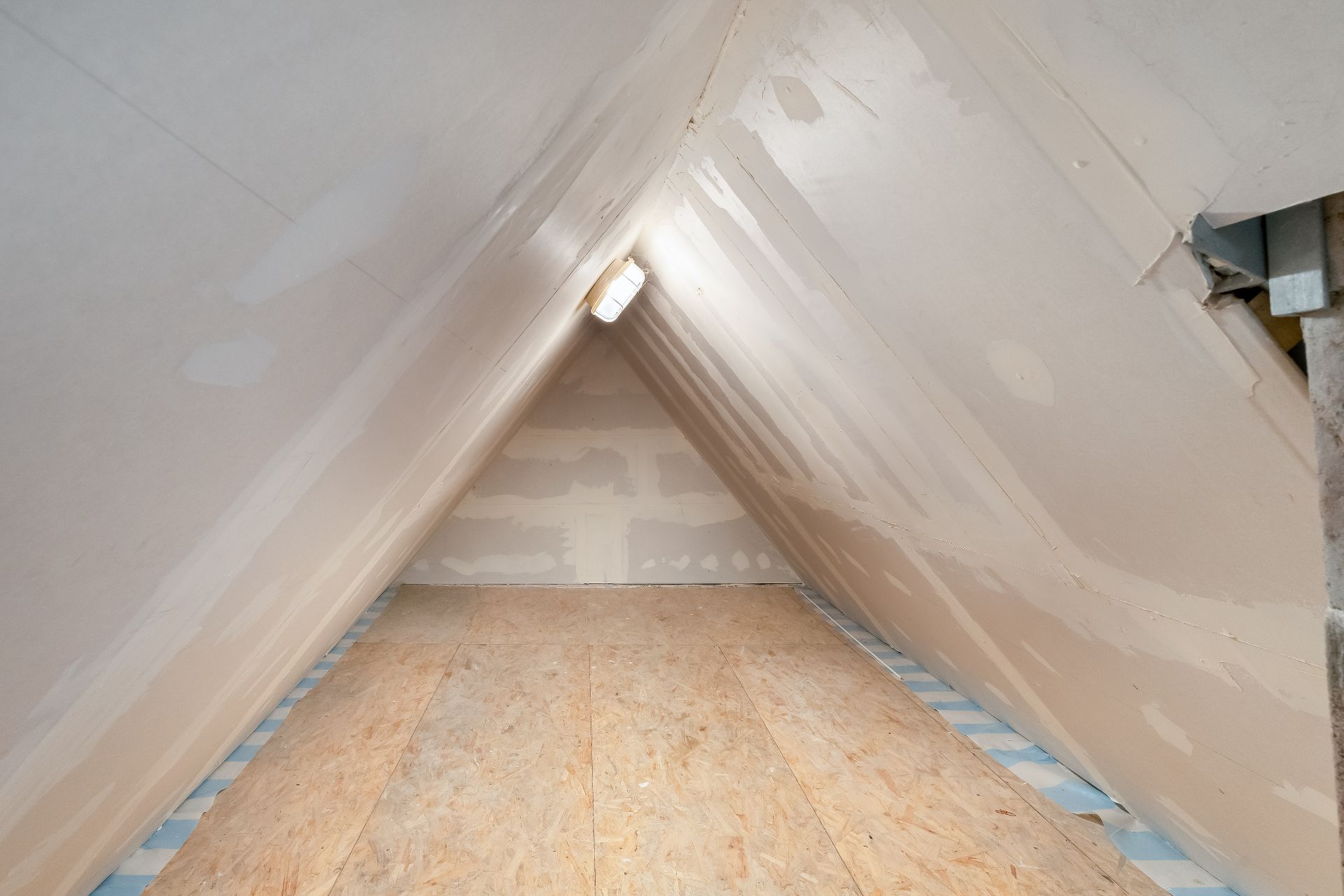 Unausgebauter Dachbodenraum mit schrägen Wänden und einfachem Holzfußboden.