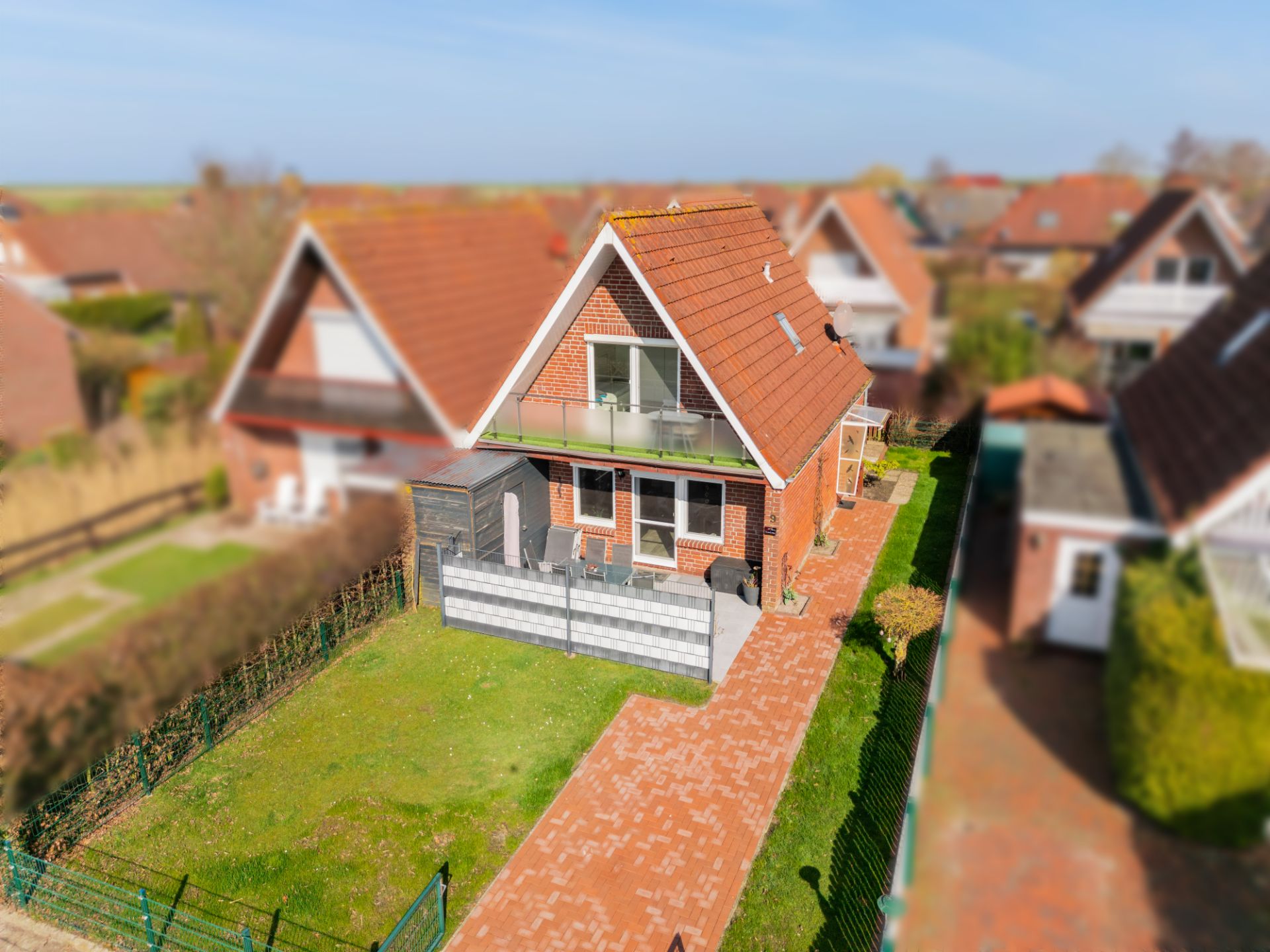 Ein rotes Einfamilienhaus mit Garten, Terrasse und Balkon in einer Wohngegend.