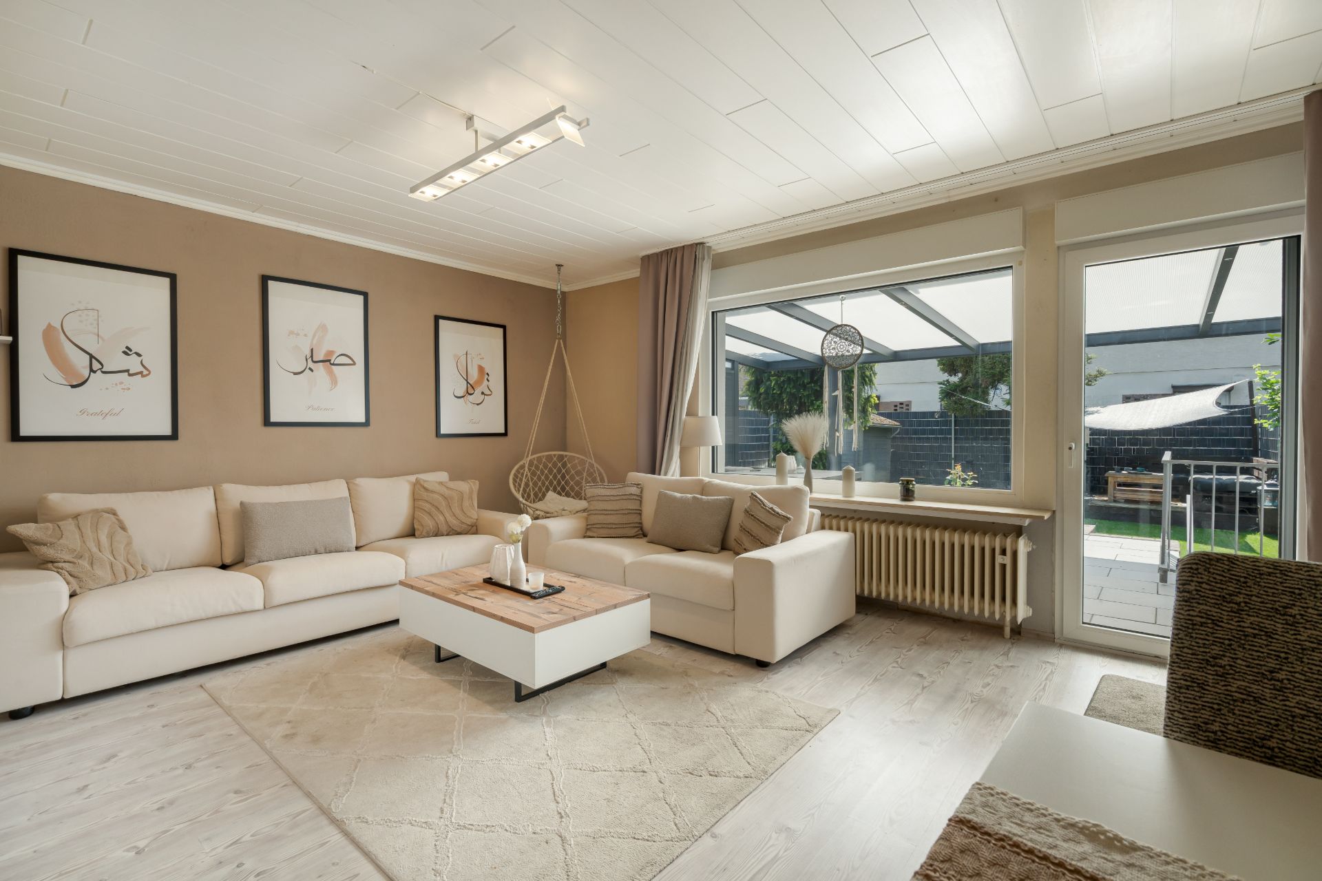 Helles Wohnzimmer mit zwei Sofas, Couchtisch, großen Fenstern und Zugang zur Terrasse.