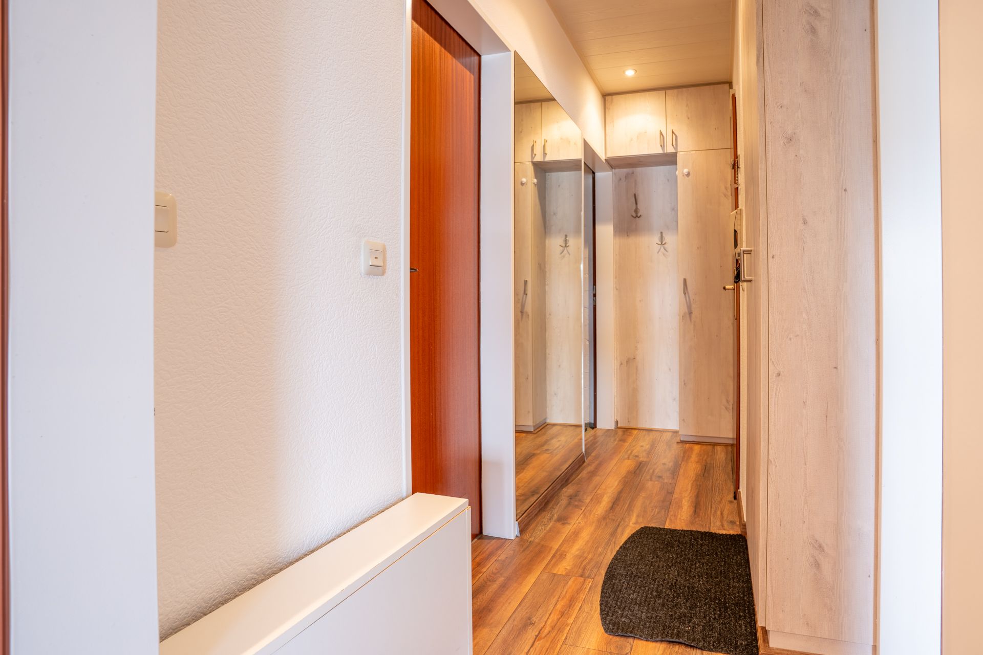 Heller Flur mit Holzfußboden, Spiegel und Einbauschränken.