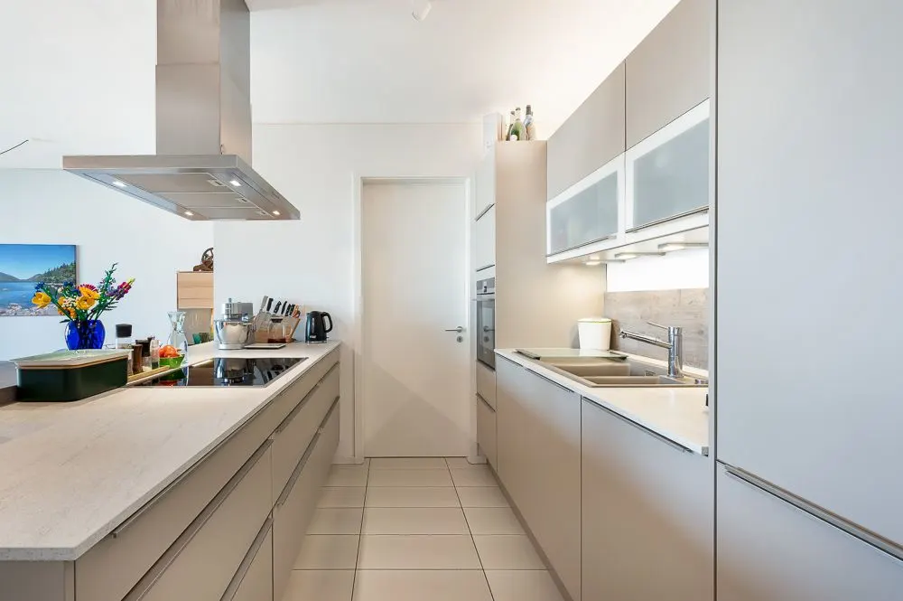 Moderne, helle Küche mit Einbauschränken, Kochinsel und Spüle.