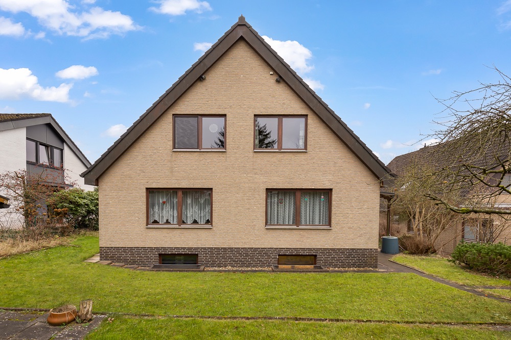 Zweistöckiges Einfamilienhaus mit Satteldach, vier Fenstern und Garten im Vordergrund.