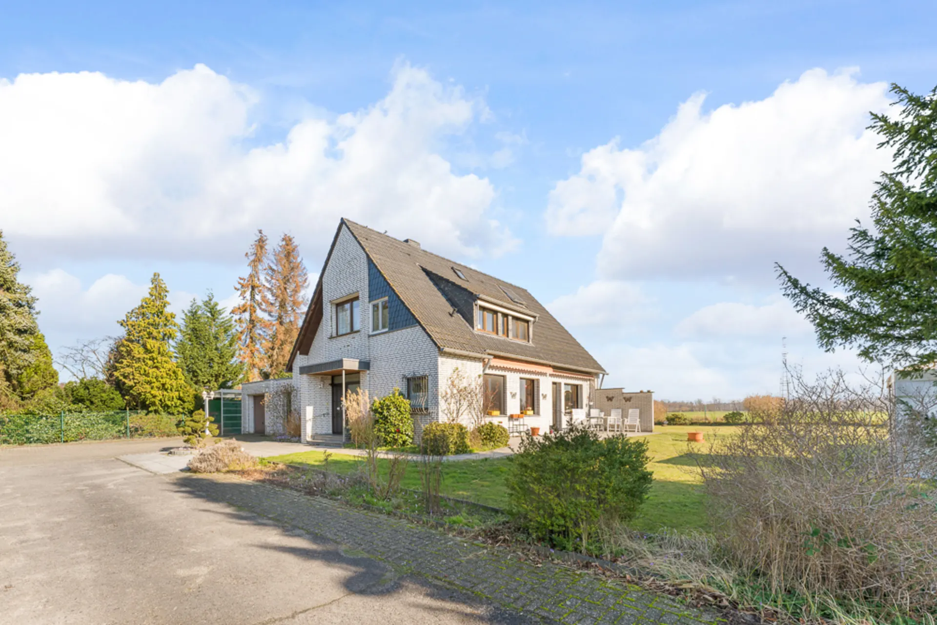 Einfamilienhaus mit Satteldach, Garten und Terrasse an einem sonnigen Tag.