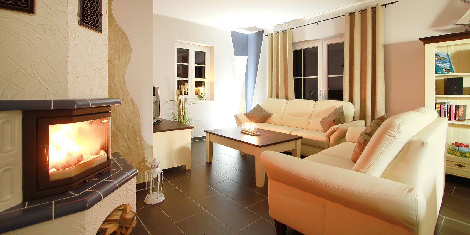 Helles Wohnzimmer mit Kamin, zwei Sofas, Couchtisch und Bücherregal.