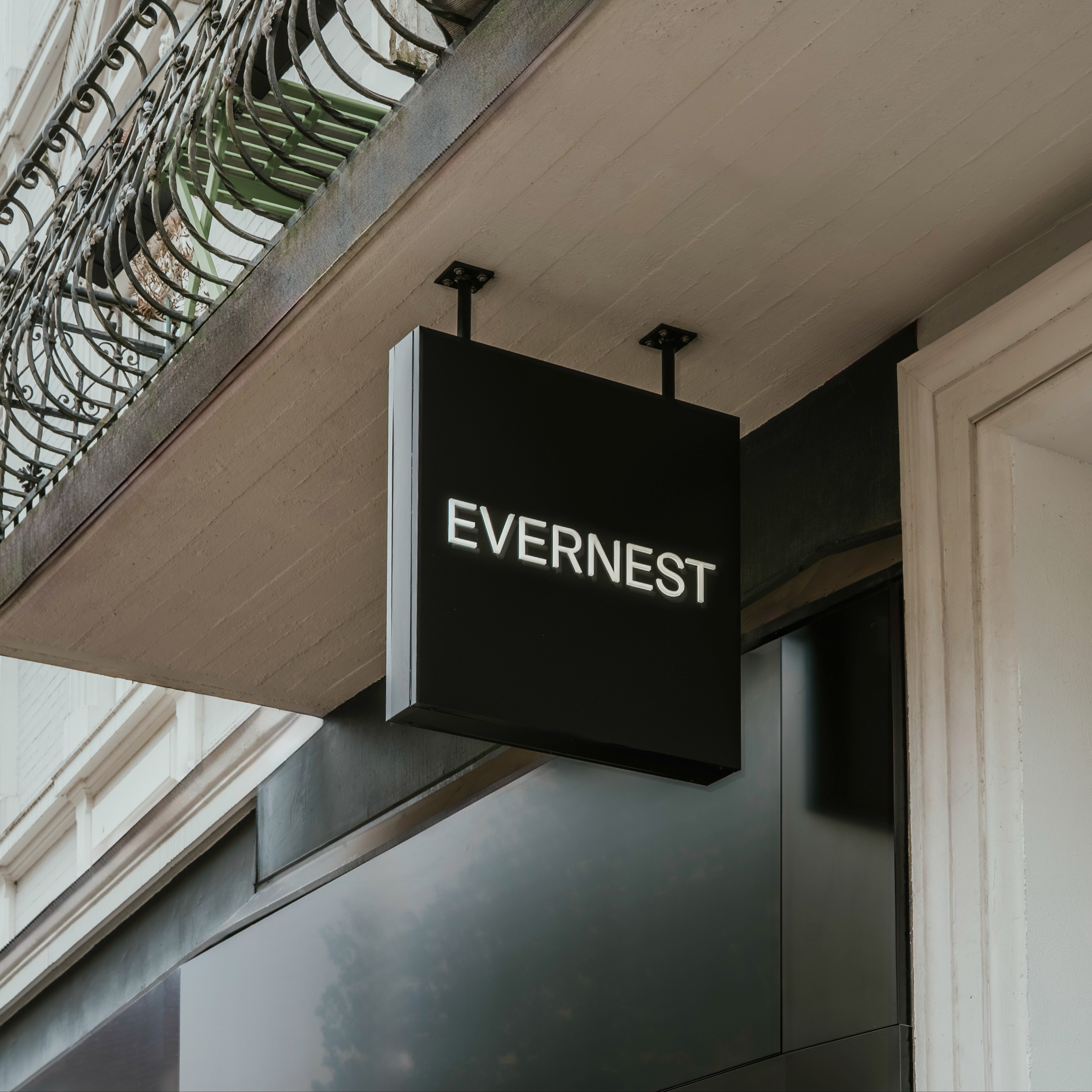 Schwarzes Schild mit weißer Aufschrift 'EVERNEST' an einer Hausfassade.