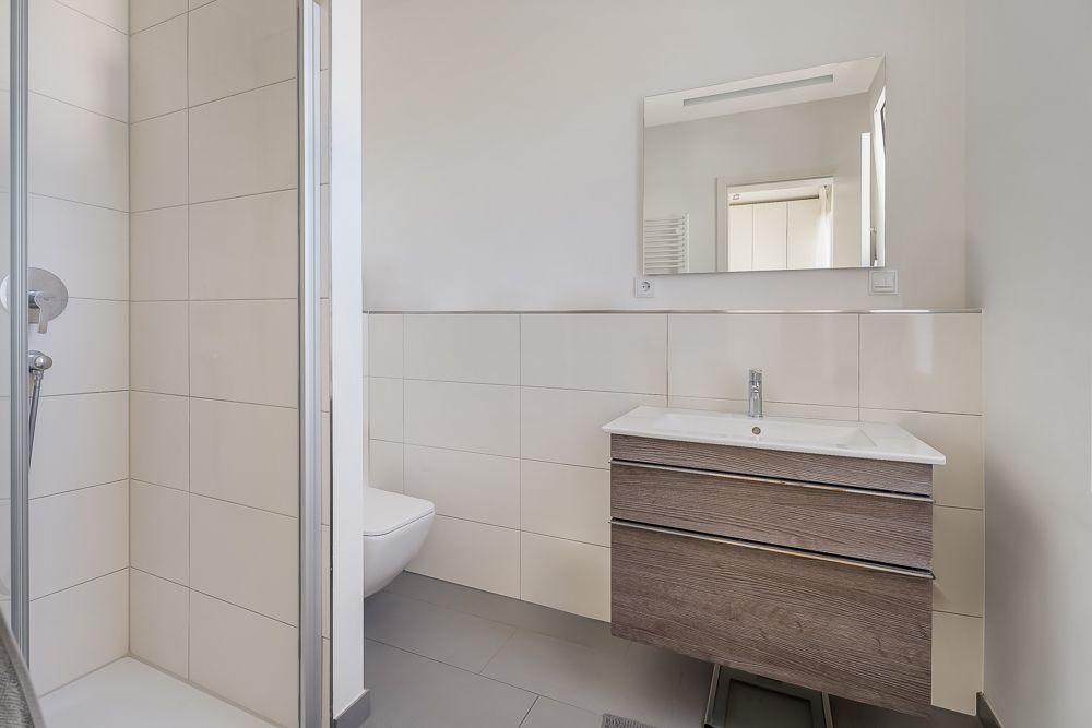 Modernes Badezimmer mit Dusche, WC, Waschbecken mit Holzunterschrank und Spiegel.