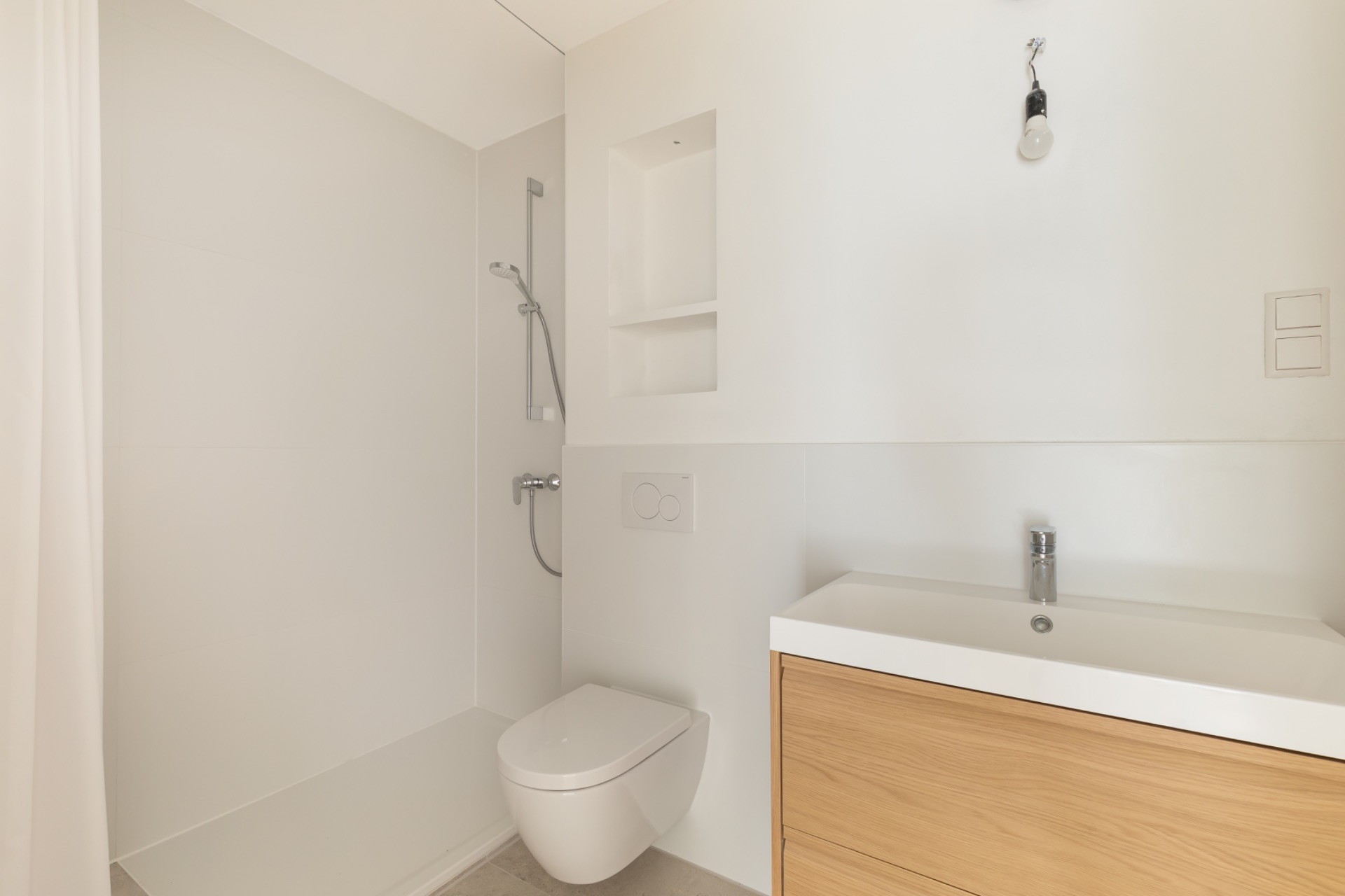 Modernes, helles Badezimmer mit Dusche, Wandtoilette und Waschbecken mit Holzunterschrank.