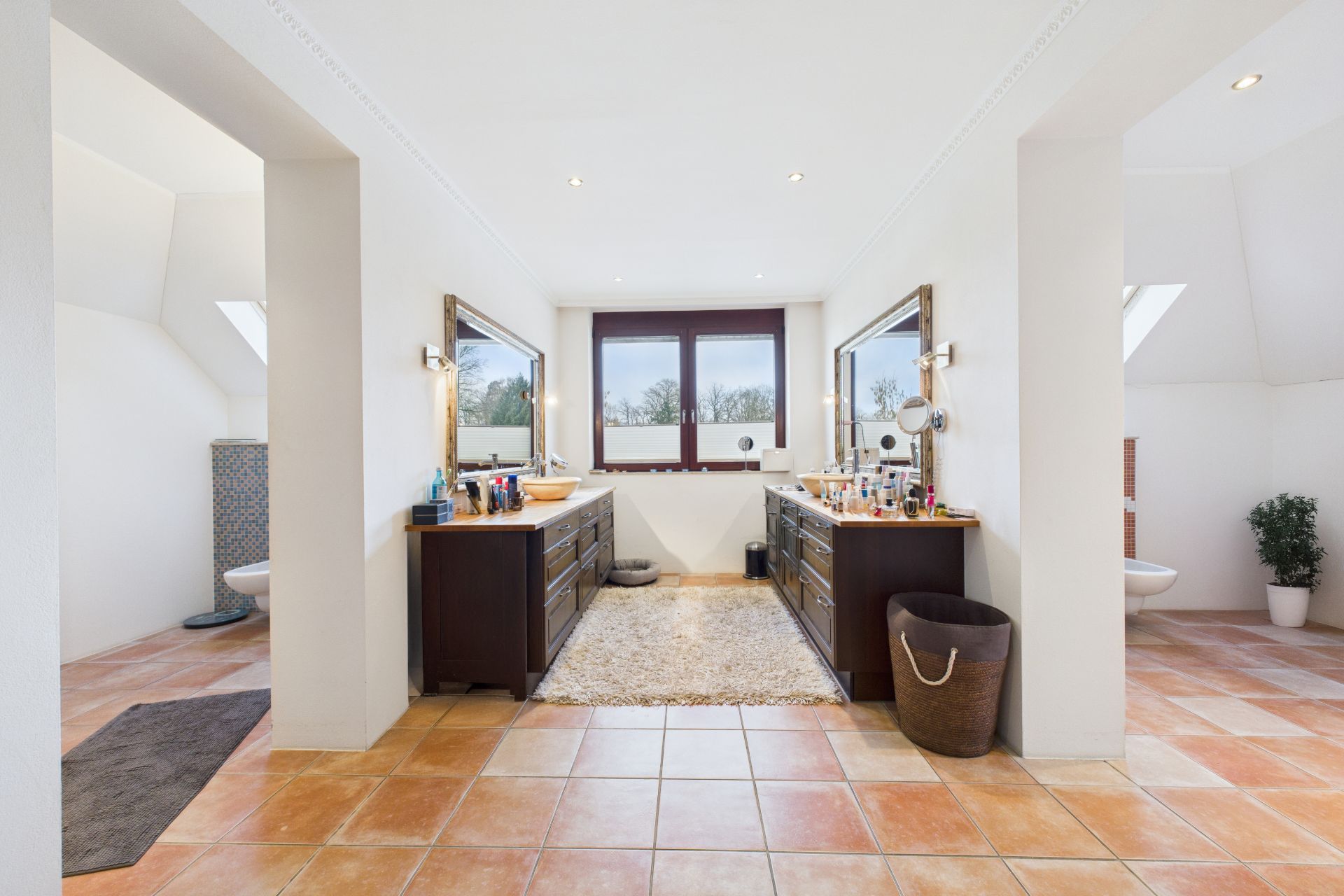Großes, helles Badezimmer mit zwei Waschbecken, Fenstern und Fliesenboden.