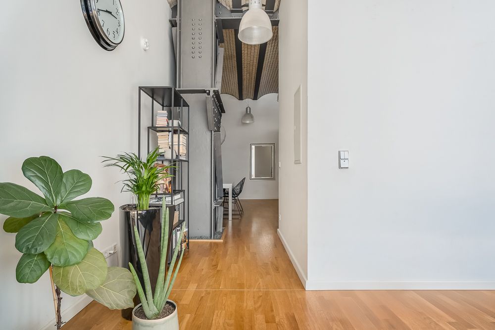 Moderner Flur mit Holzboden, Pflanzen, Regal und sichtbaren Deckenbalken.