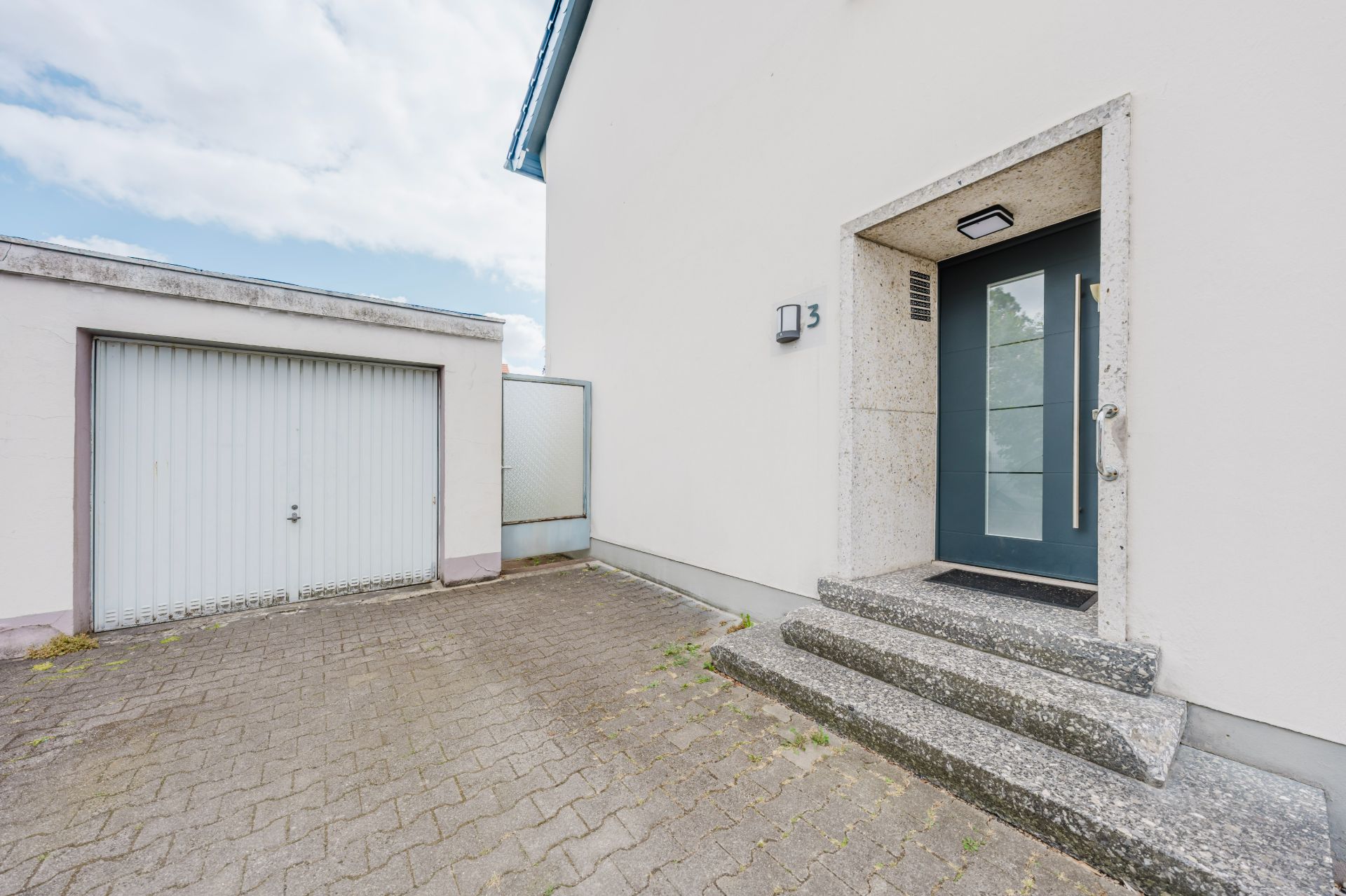 Eingangsbereich eines Hauses mit Stufen und angrenzender Garage.