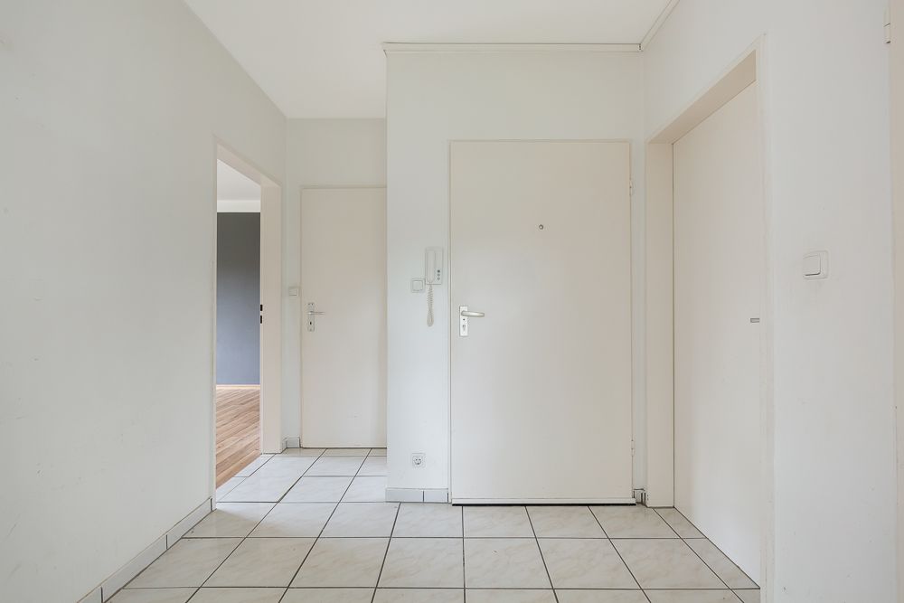 Heller Flur mit weißen Türen und gefliestem Boden in einer Wohnung.