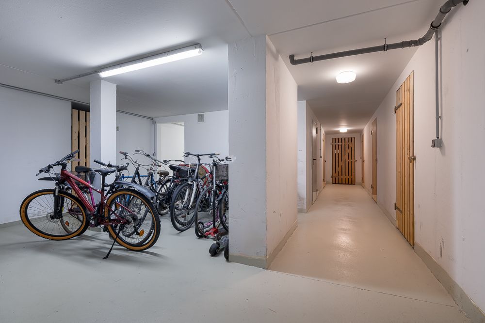 Fahrradkeller mit mehreren abgestellten Fahrrädern und Flur mit Holztüren.