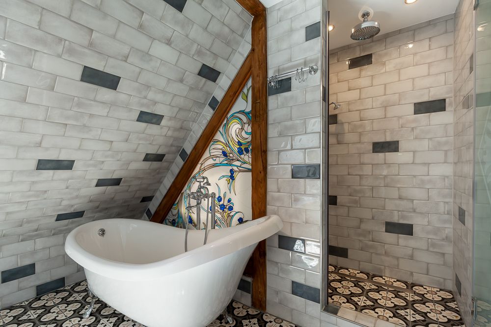 Modernes Bad mit freistehender Badewanne, gemusterter Fliesenwand und Dusche.