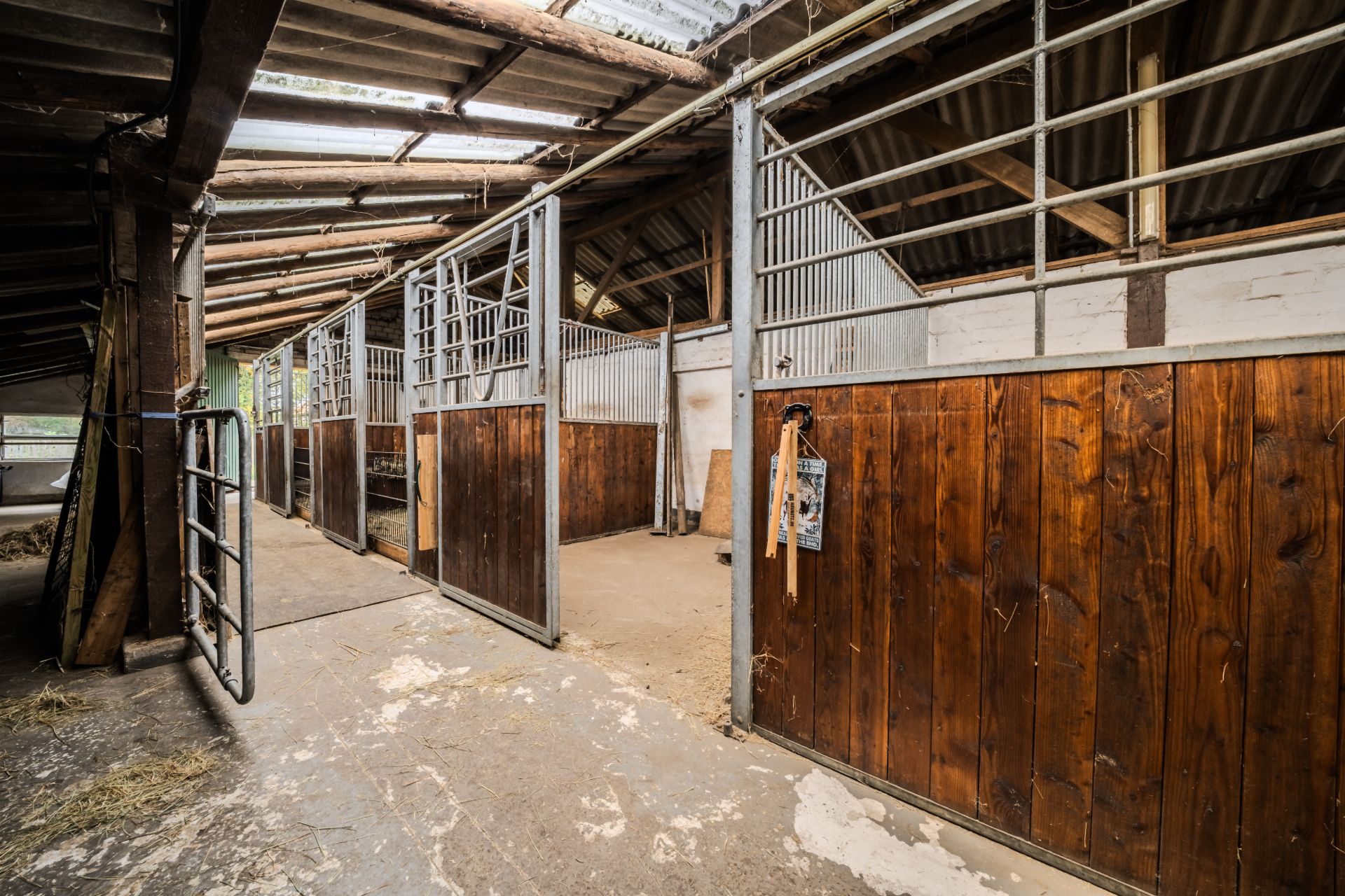 Innenansicht eines Stalls mit mehreren Pferdeboxen und Holzwänden.