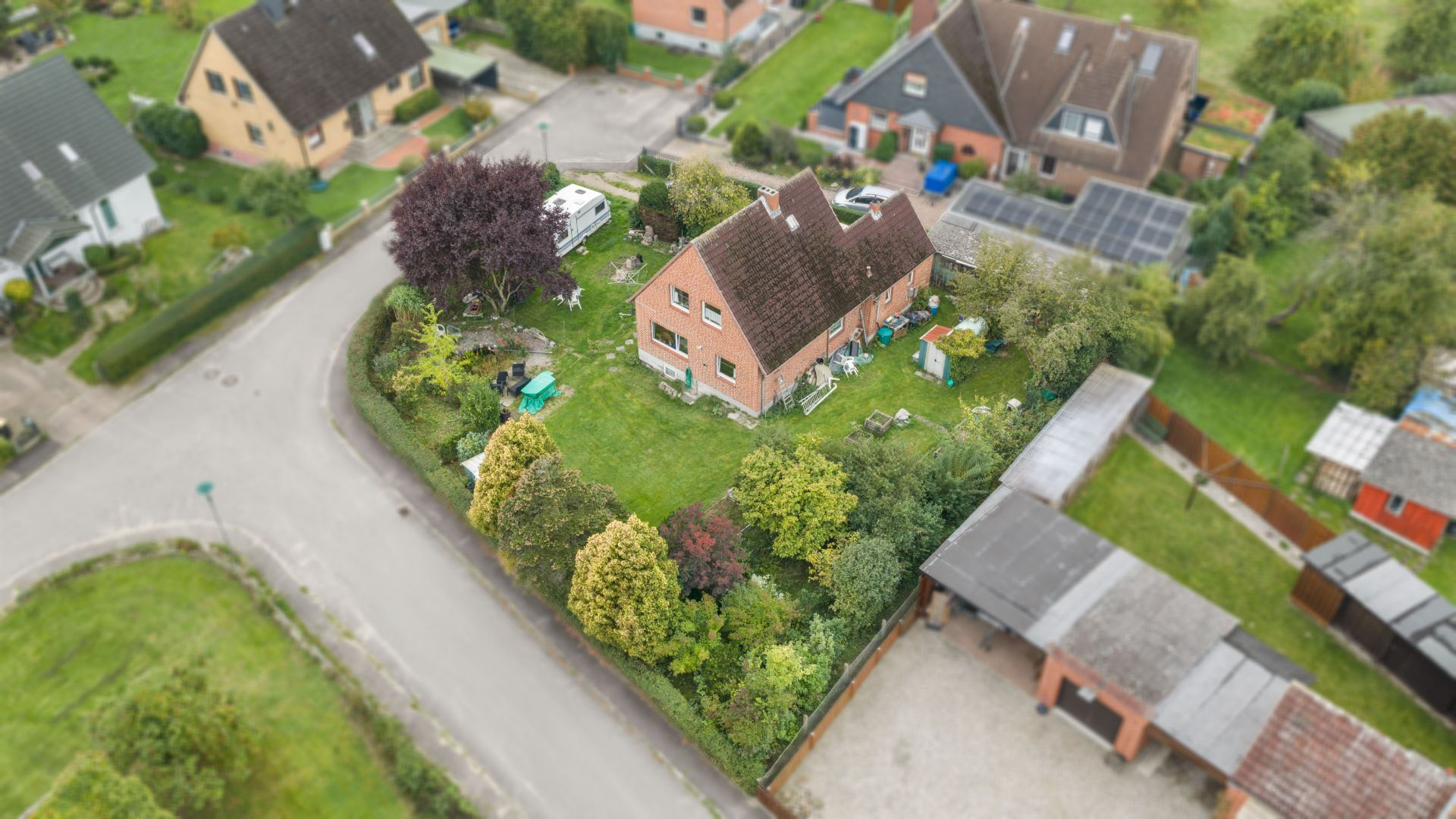 Luftaufnahme eines Einfamilienhauses mit großem Garten, umgeben von Bäumen und Hecken.