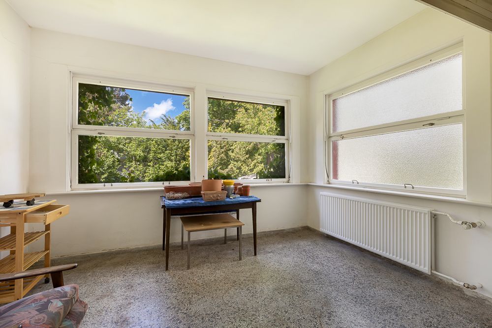 Heller Raum mit großen Fenstern, Tisch, Stuhl und Heizung, Blick ins Grüne.
