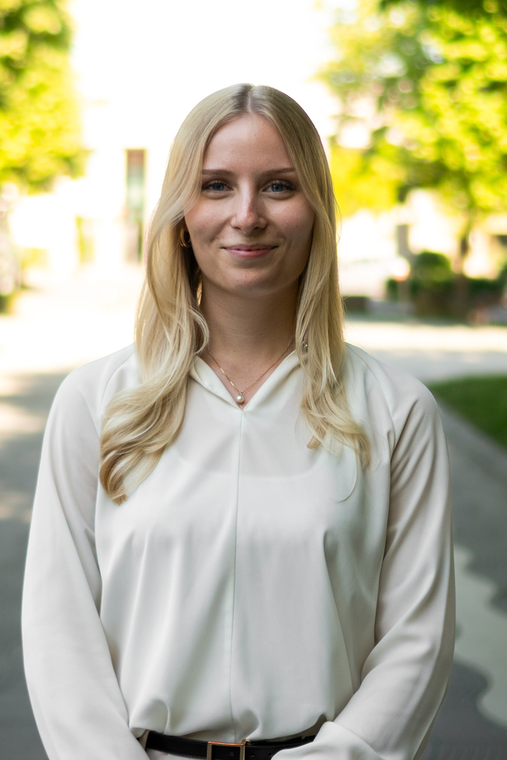 Eine junge Frau mit langen blonden Haaren steht vor einer Holztreppe.