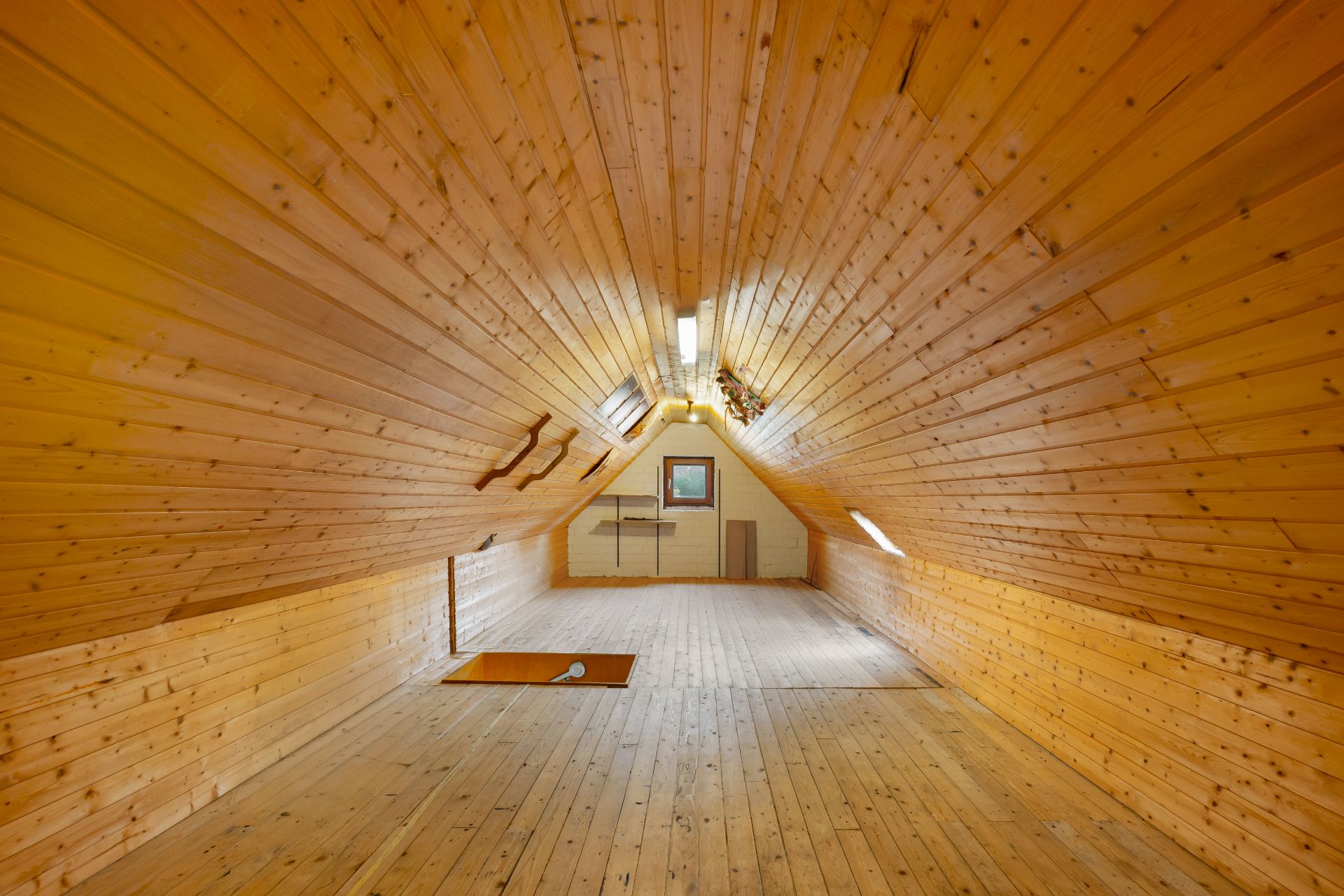 Leerer Dachbodenraum mit Holzverkleidung und Dachfenstern.
