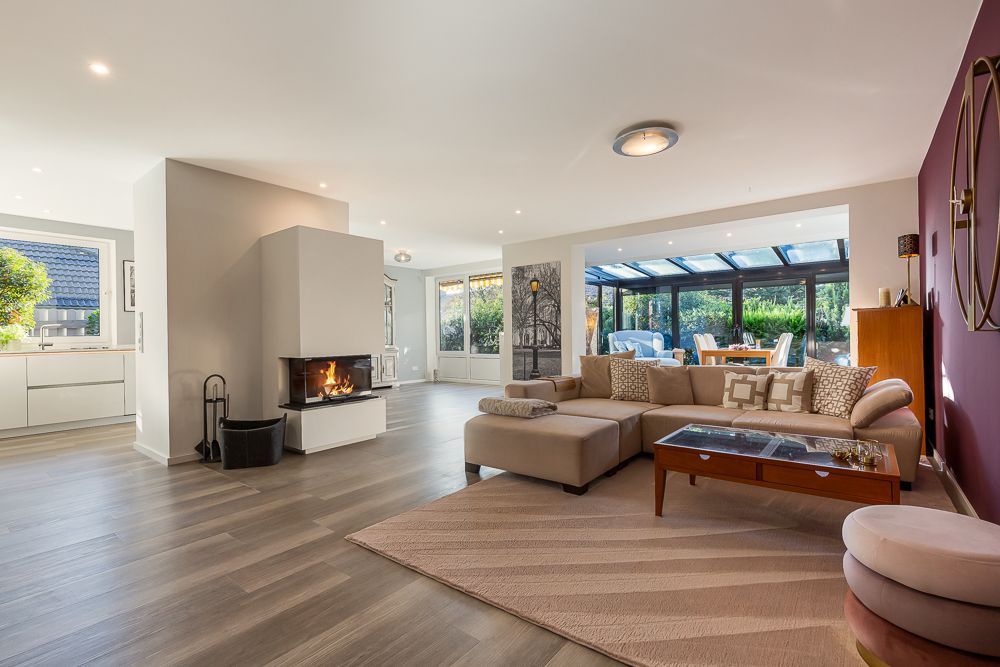 Modernes Wohnzimmer mit Kamin, Sofa, Couchtisch und großem Fenster zum Garten.