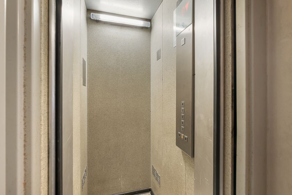 Kleiner Aufzug mit Wandpaneelen, Bedienfeld und Deckenleuchte.