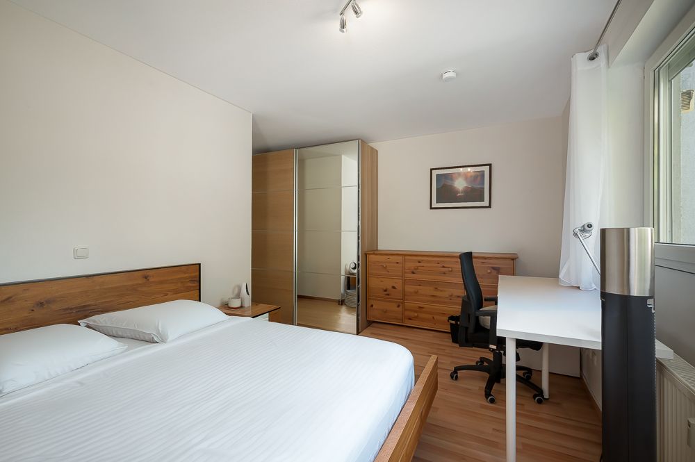 Schlafzimmer mit Doppelbett, Schreibtisch, Stuhl, Kommode und Kleiderschrank.