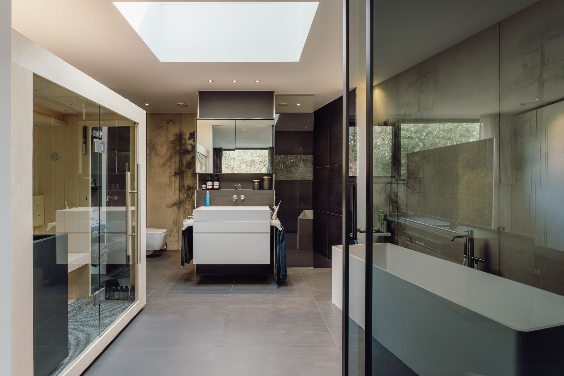 Modernes Badezimmer mit freistehender Badewanne, Sauna, großem Spiegel und Oberlicht.