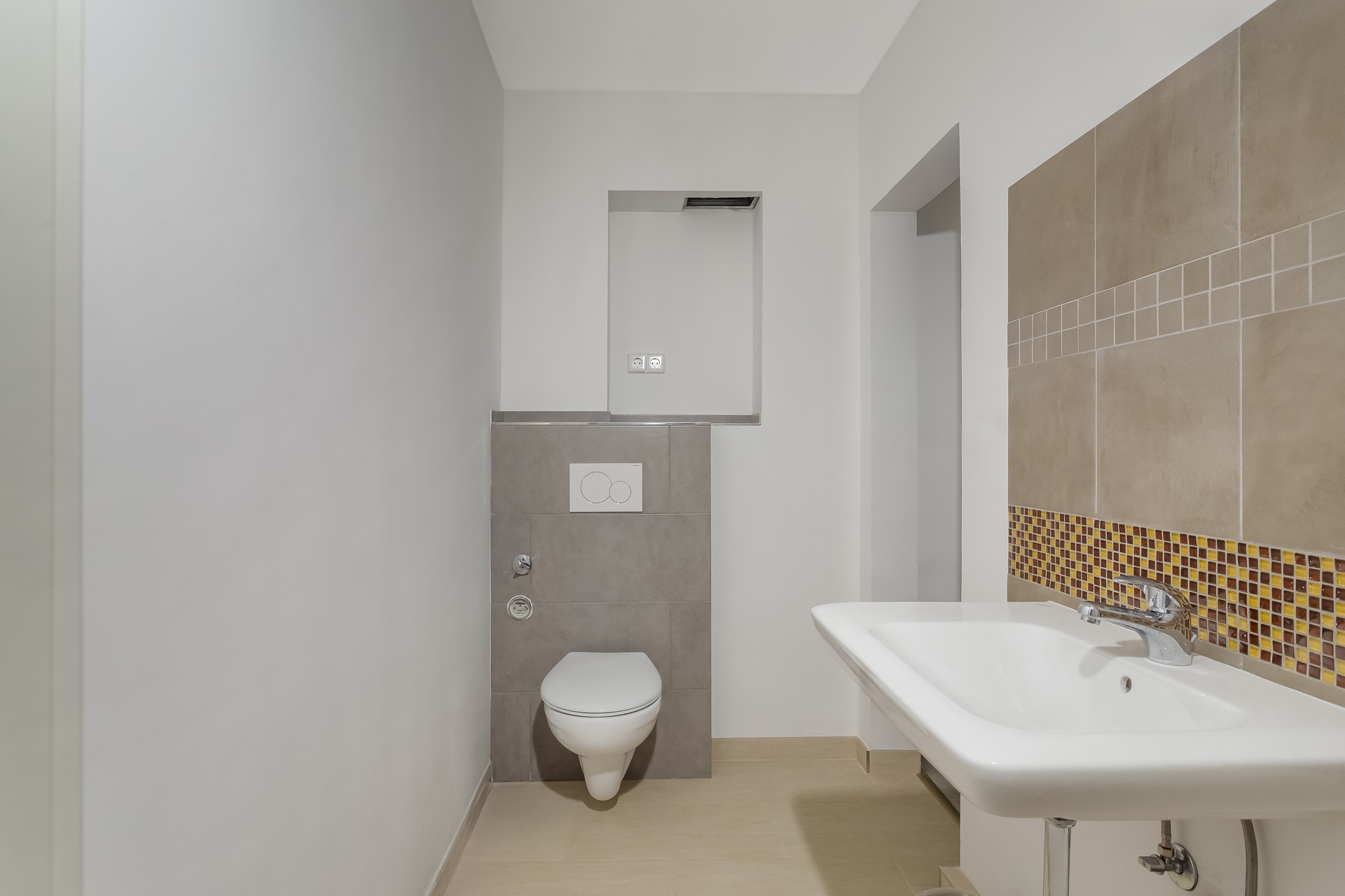 Modernes Badezimmer mit Wandtoilette und weißem Waschbecken, Fliesen an der Wand.