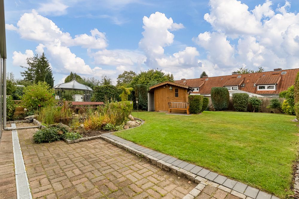 Gepflegter Garten mit Rasen, Gartenhaus, Pavillon und kleinem Teich bei Reihenhäusern.