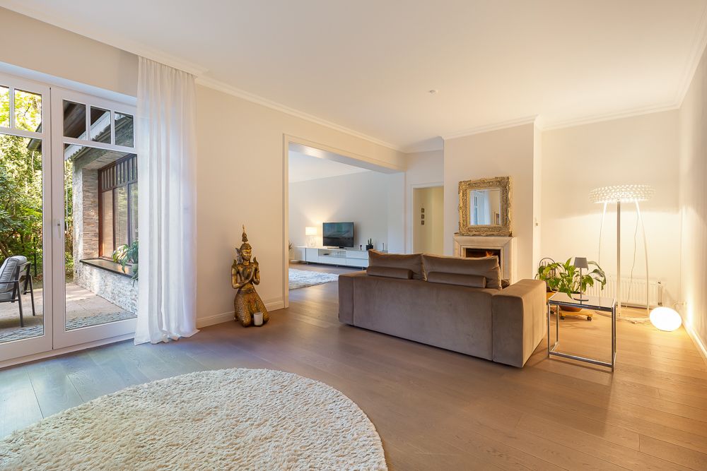 Helles Wohnzimmer mit Sofa, Teppich, großer Fensterfront und Zugang zur Terrasse.