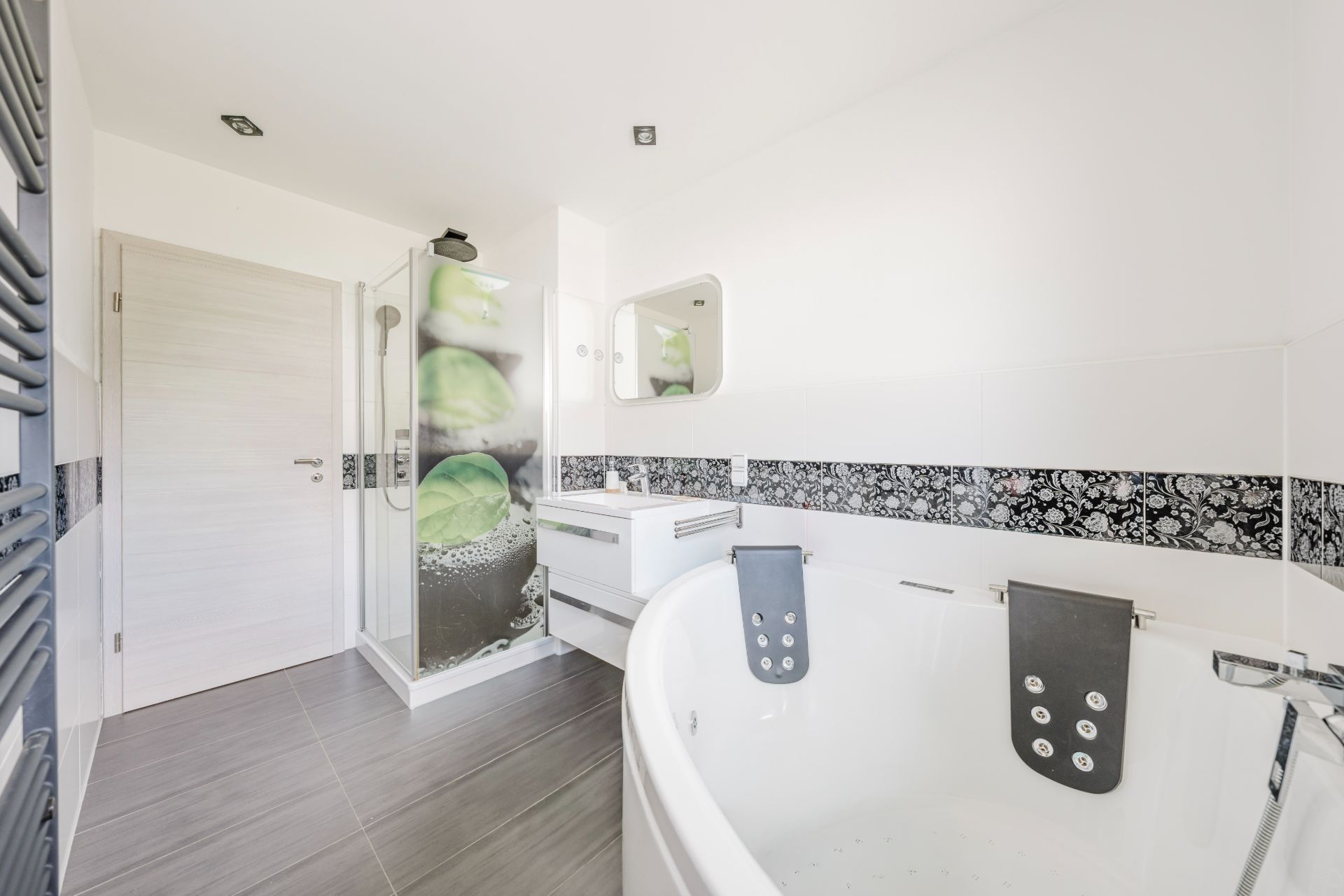 Modernes Badezimmer mit Badewanne, Dusche, Waschbecken und großem Spiegel.