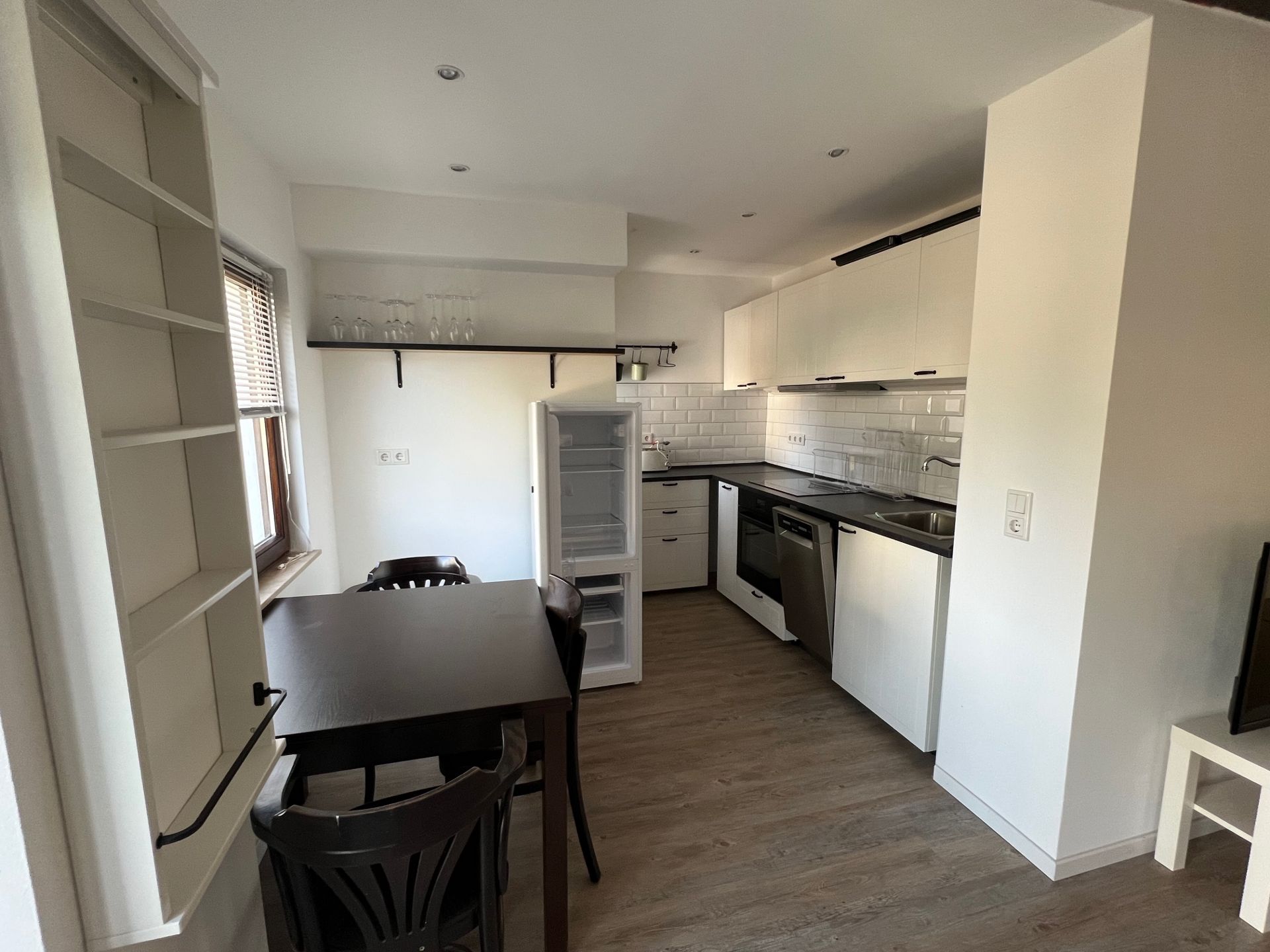 Moderne Wohnküche mit Esstisch, offenen Regalen, Kühlschrank und Elektrogeräten.