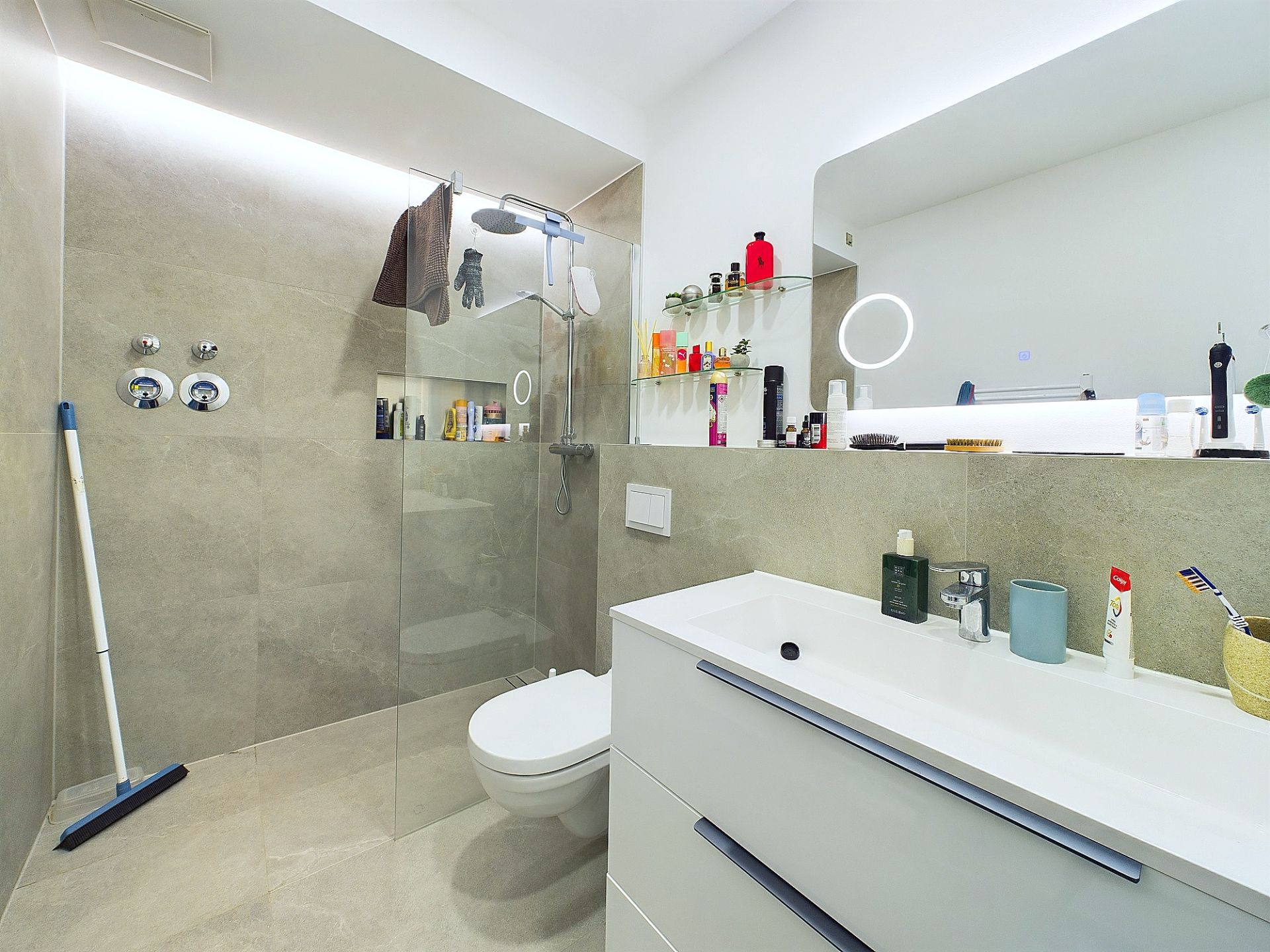 Modernes Badezimmer mit großer Dusche, wandhängendem WC und Waschbecken mit Spiegel.