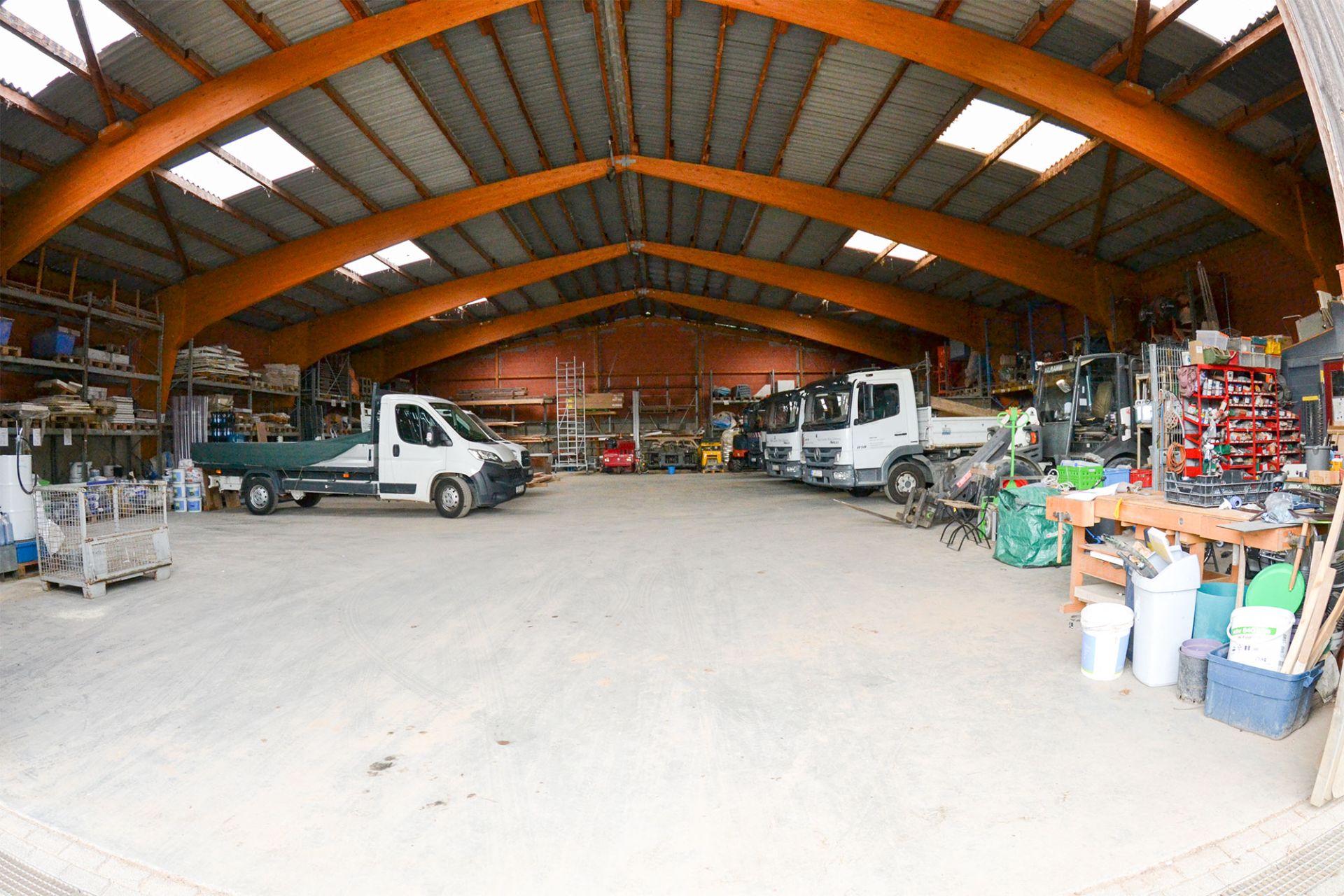 Große Lagerhalle mit Fahrzeugen, Regalen und verschiedenen Werkzeugen.
