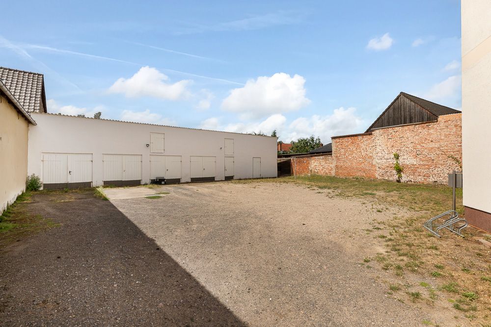Großer, offener Hof mit Schotterboden, mehreren Garagentoren und einer roten Backsteinmauer.