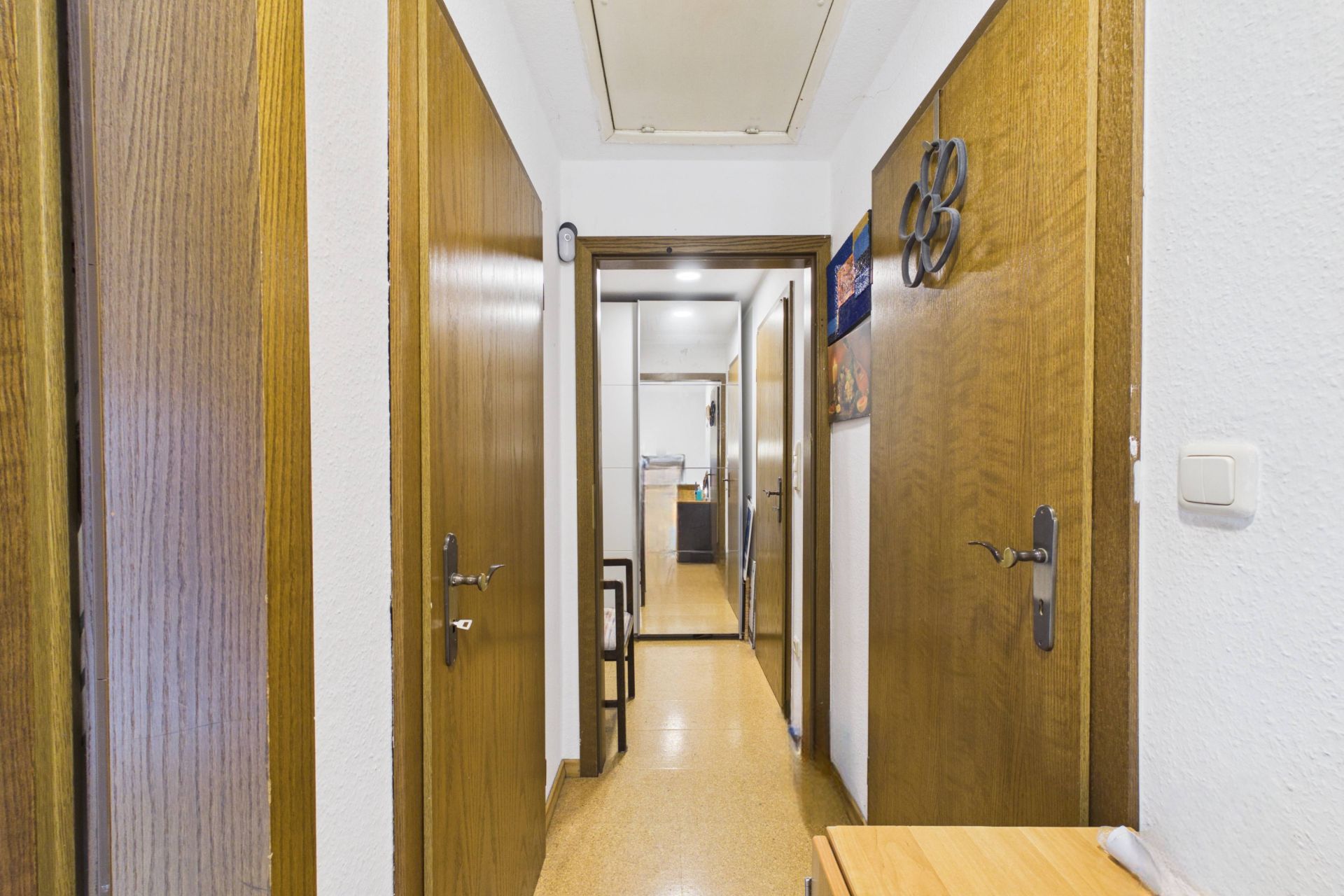 Heller Flur mit Holztüren beidseitig und Blick in angrenzende Räume einer Wohnung.