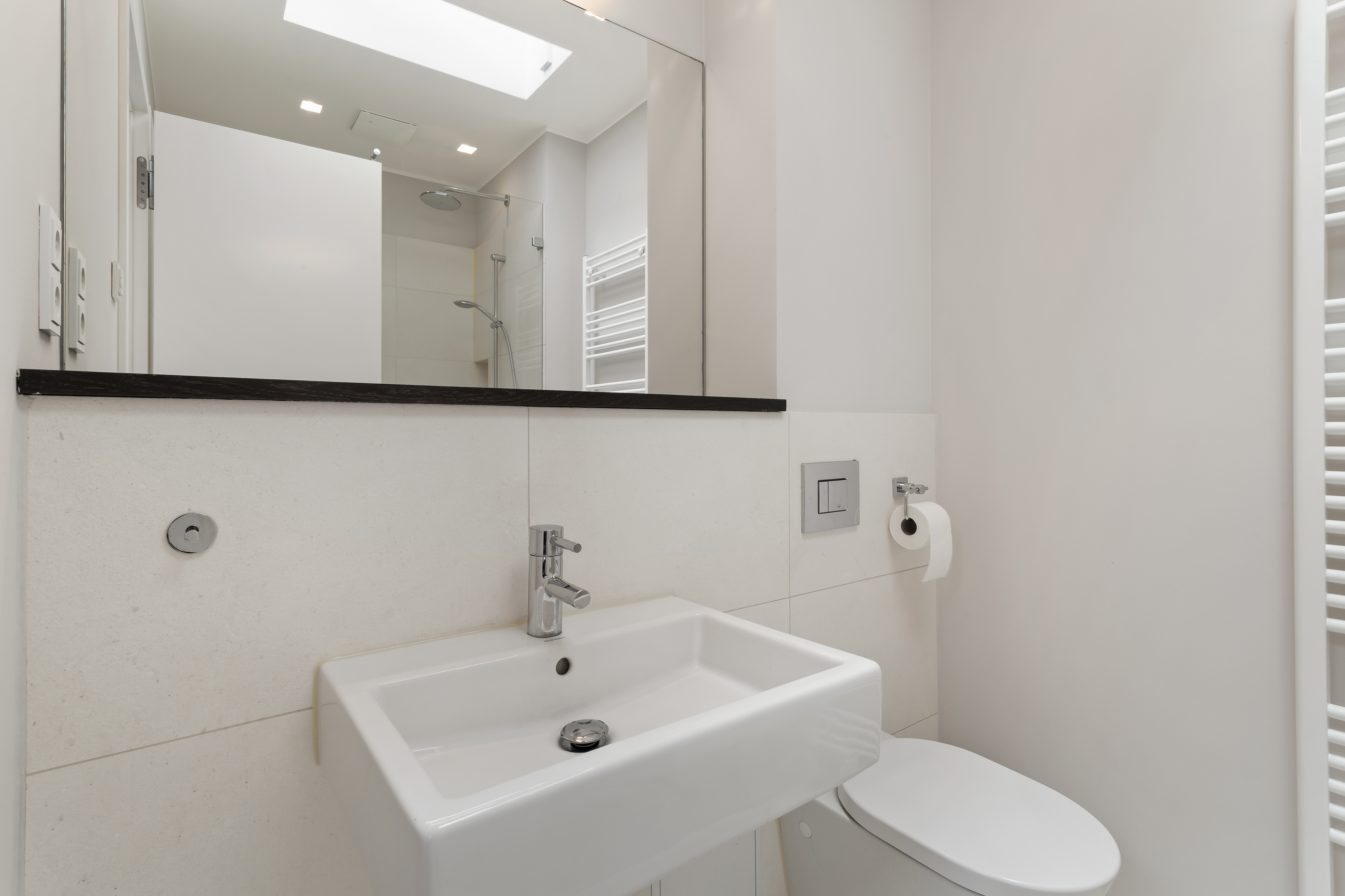 Modernes Badezimmer mit Waschbecken, Spiegel, Toilette und Dusche.