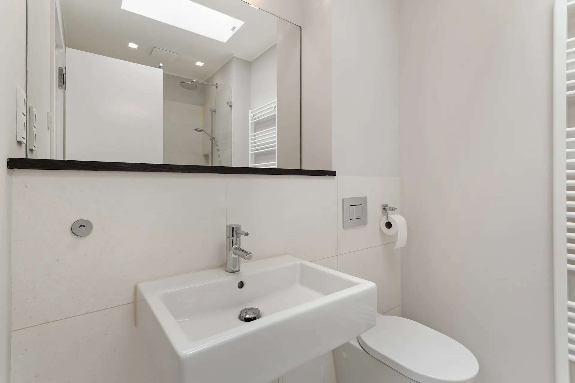 Modernes Badezimmer mit Waschbecken, Spiegel, Toilette und Dusche.