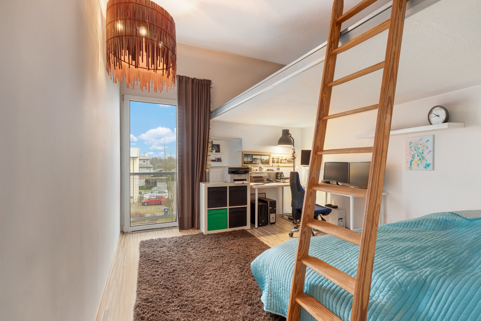 Helles Zimmer mit Hochbett, Schreibtisch, Leiter, Teppich und großem Fenster.