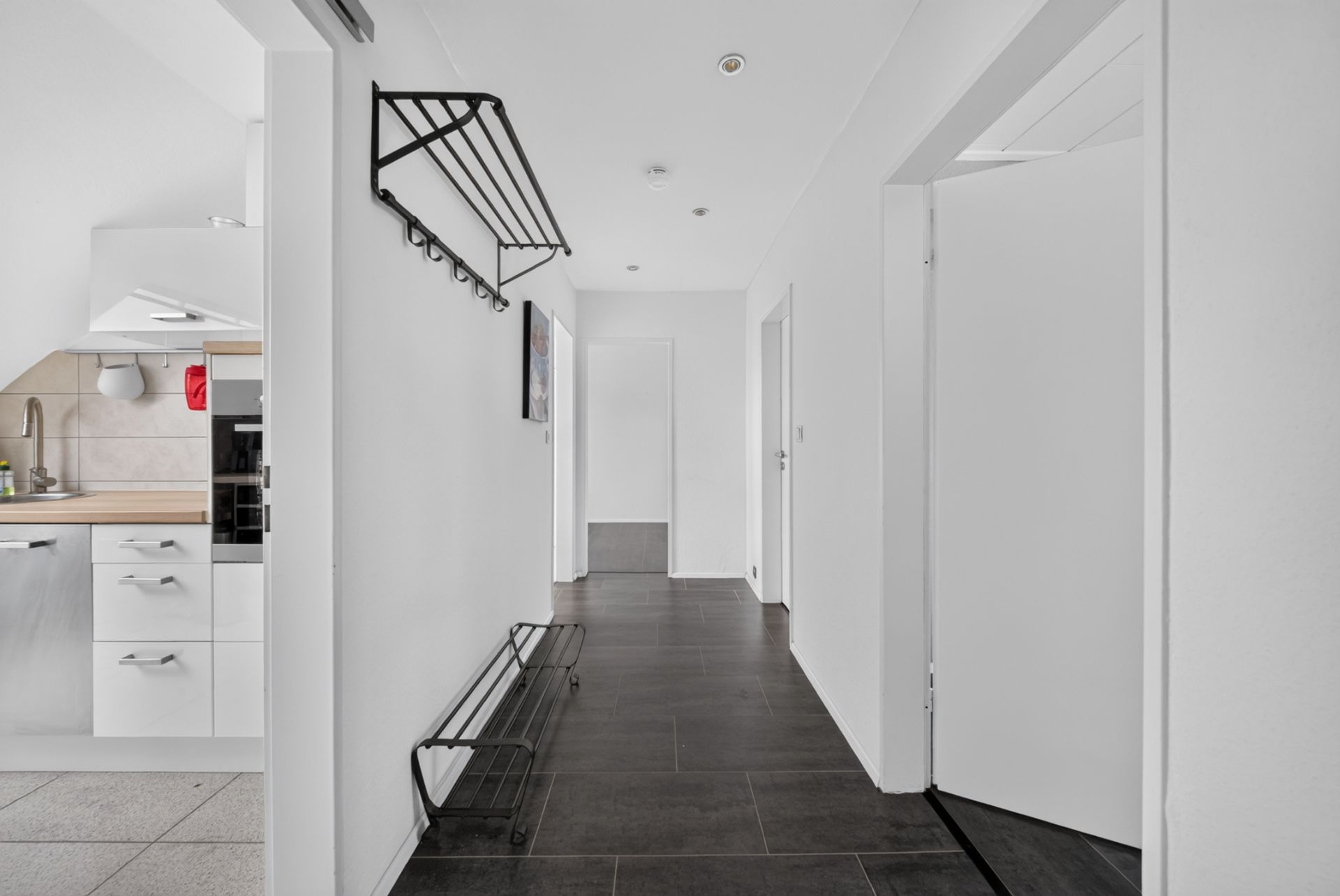 Heller Flur mit Garderobe und Blick in eine moderne Küche mit weißen Schränken.