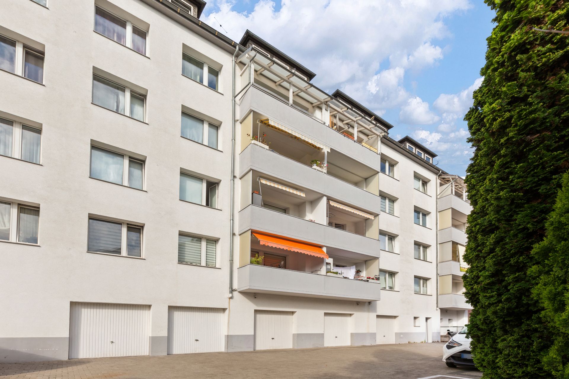 Mehrfamilienhaus mit Balkonen und mehreren Garagentoren im Erdgeschoss.